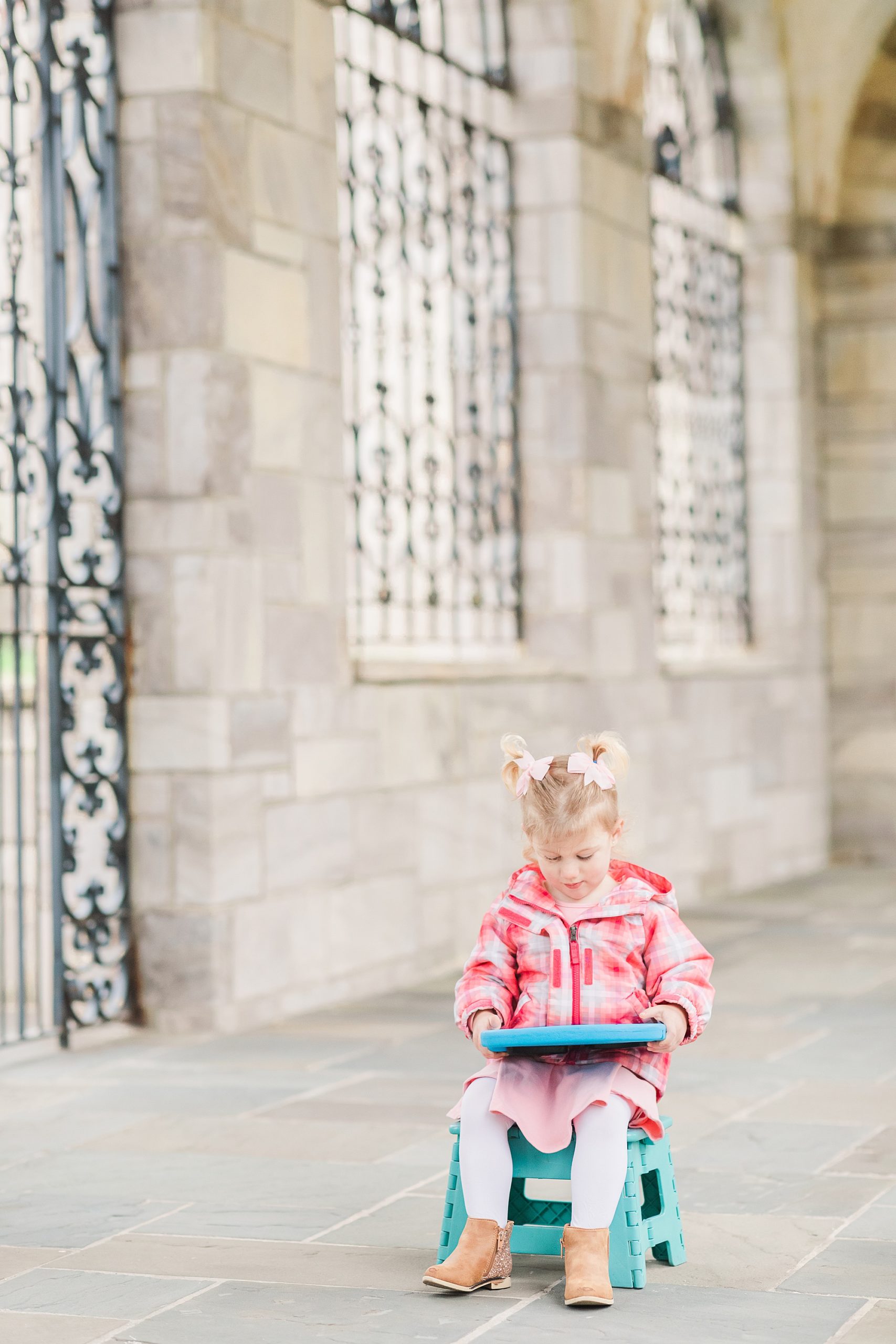 little girl sits watching tablet during family photos