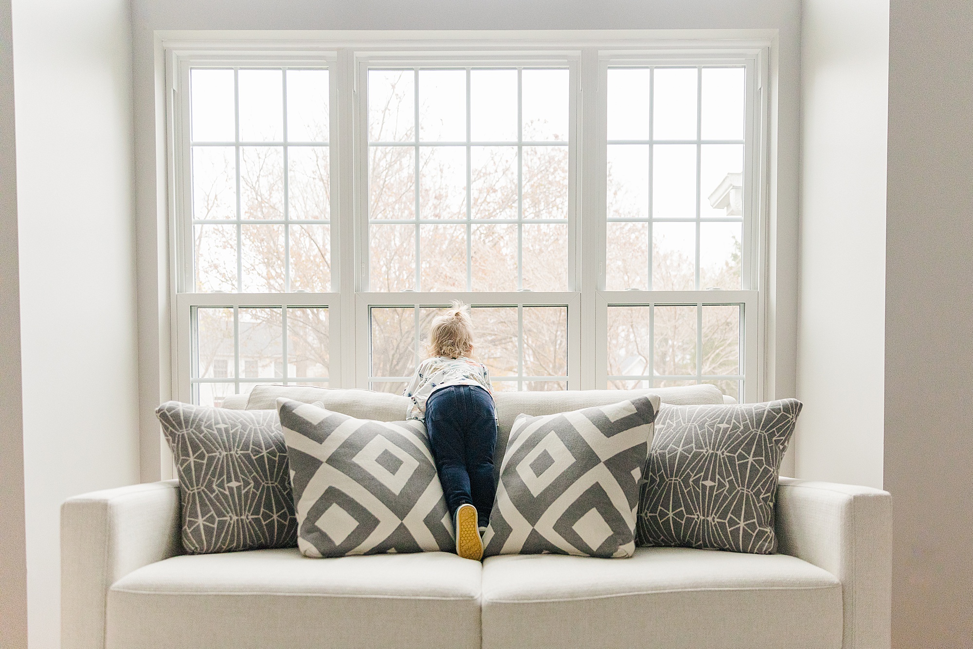 Toddler stands on couch during MD family photos 