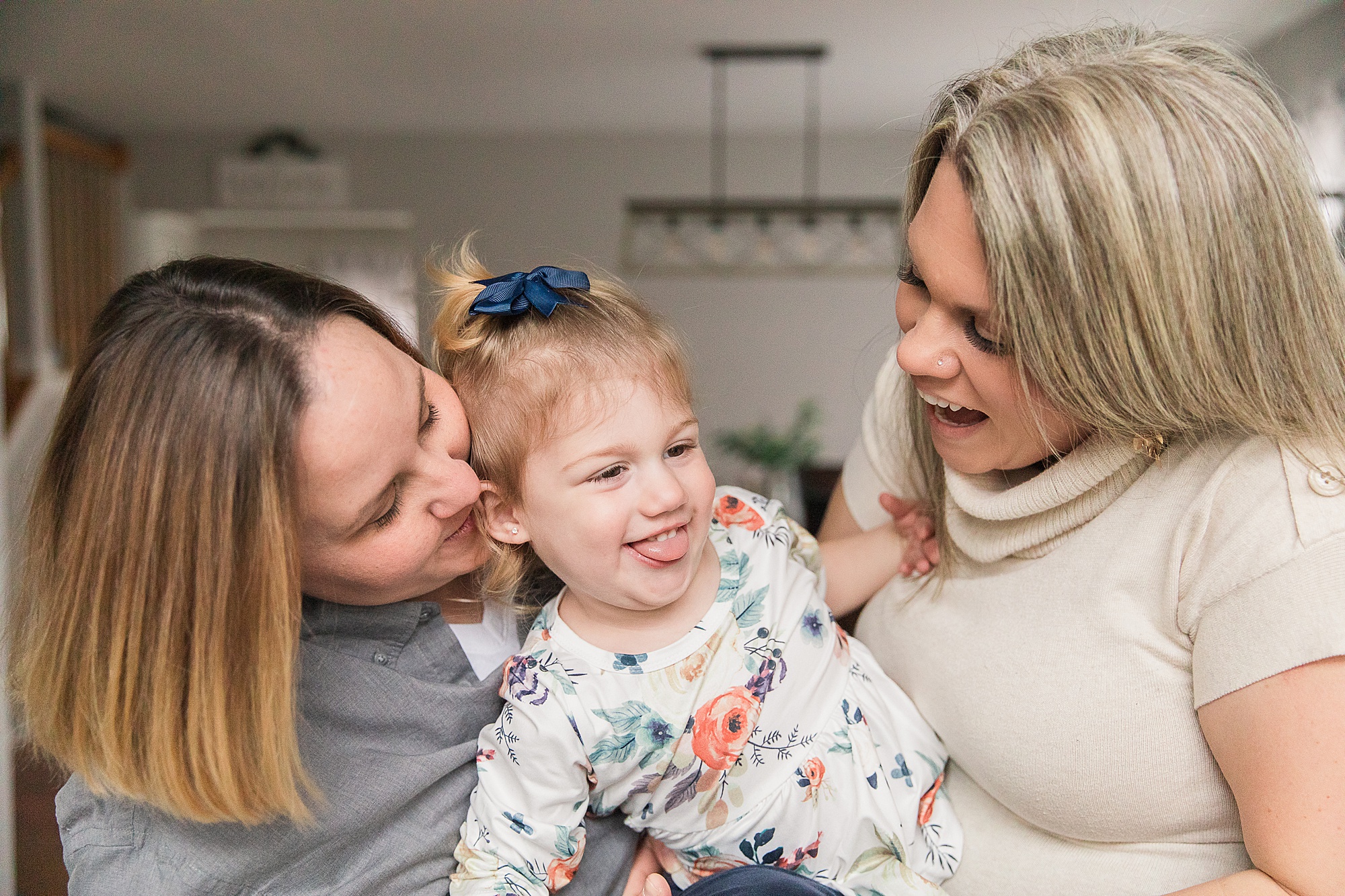daughter laughs with two moms during lifestyle family photos