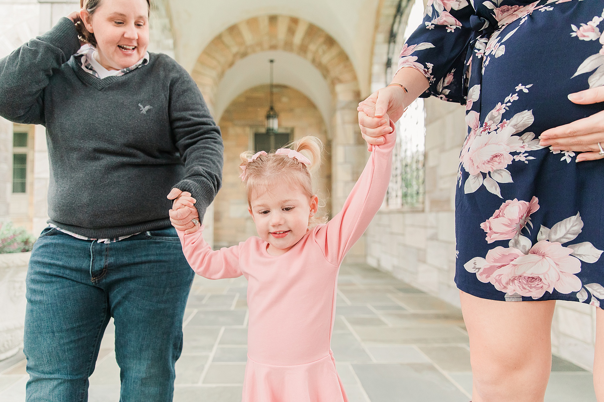 women walk with daughter during family photos at Shrine of St. Anthony