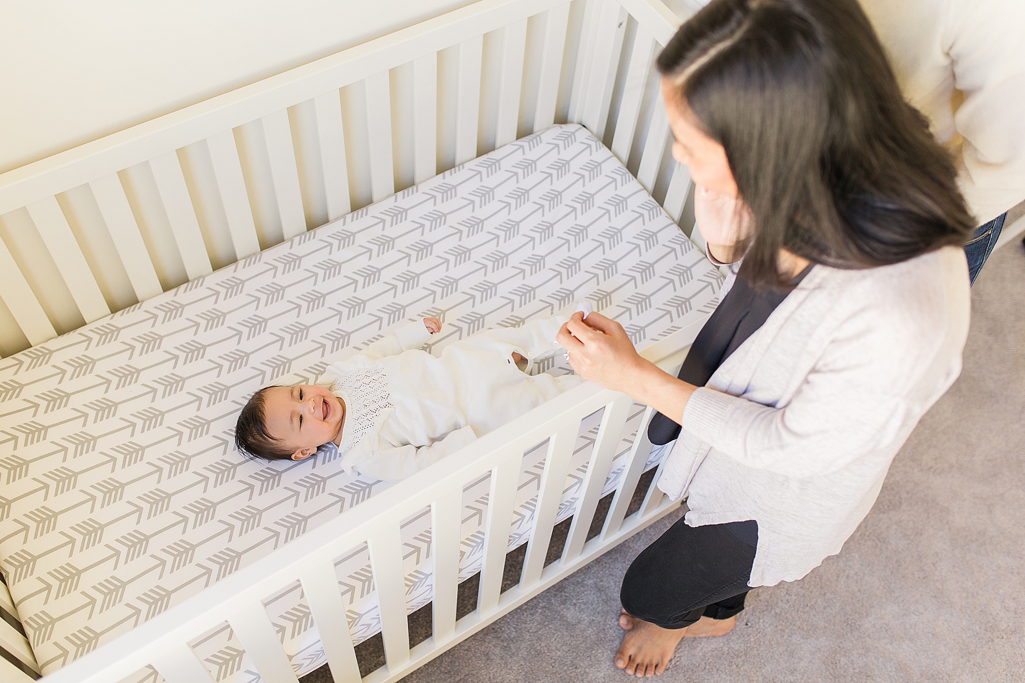 mom looks into crib at daughter during family photos
