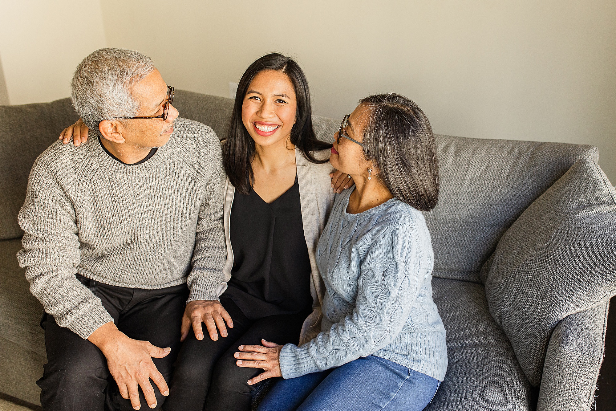 adult daughter sits with parents on couch at home