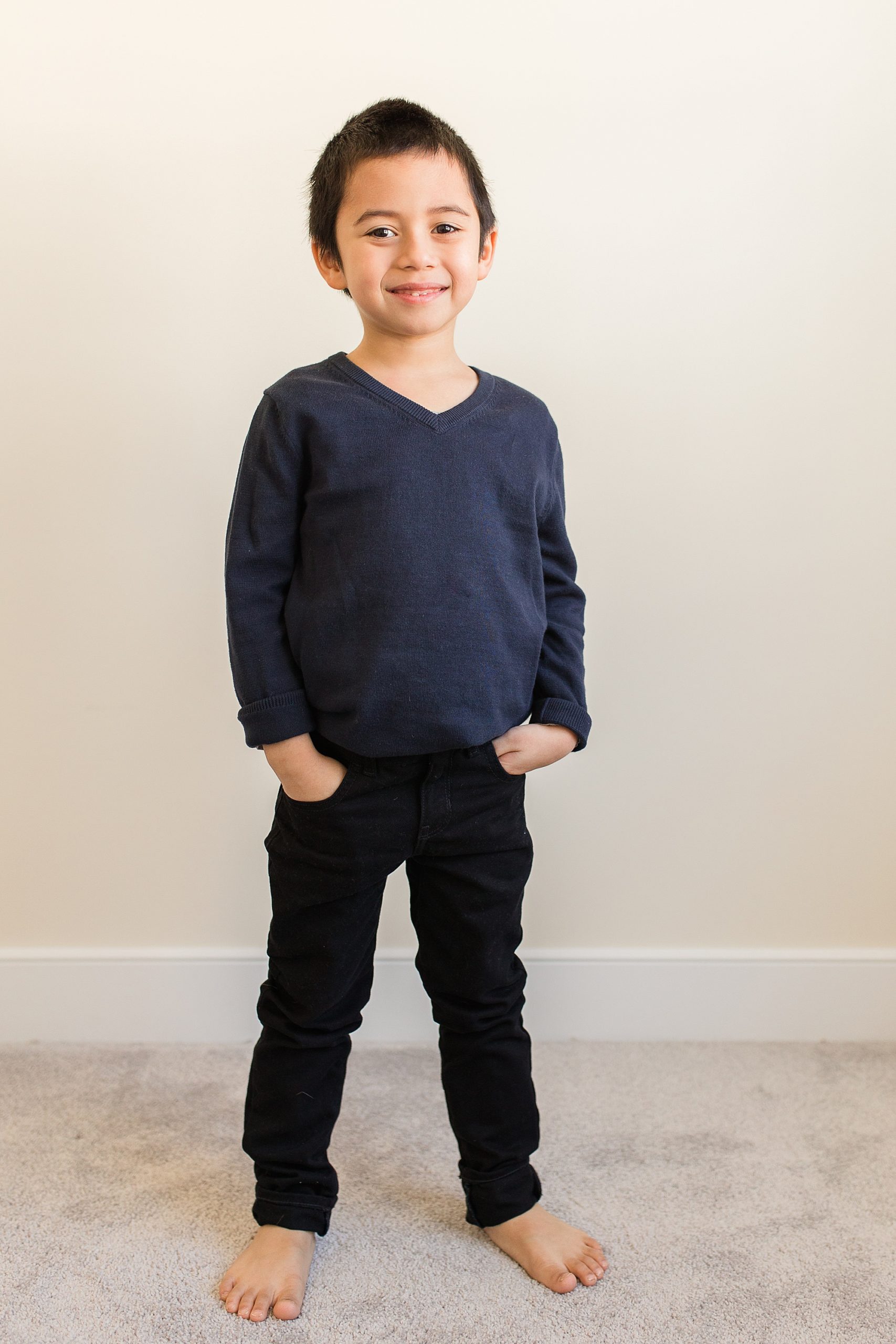 toddler stands in living room in dark shirt and pants 