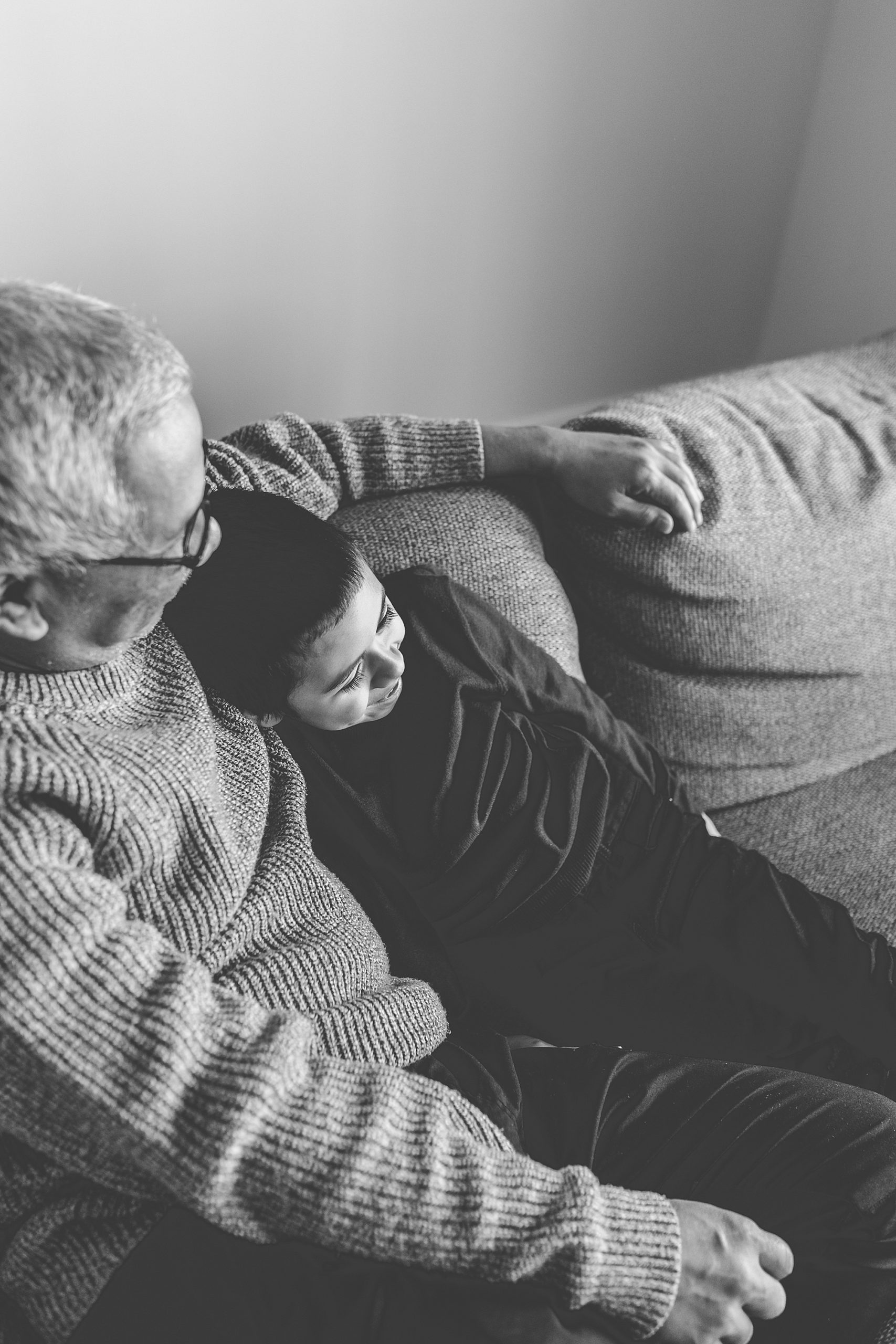 grandson leans against grandpa during family photos on couch