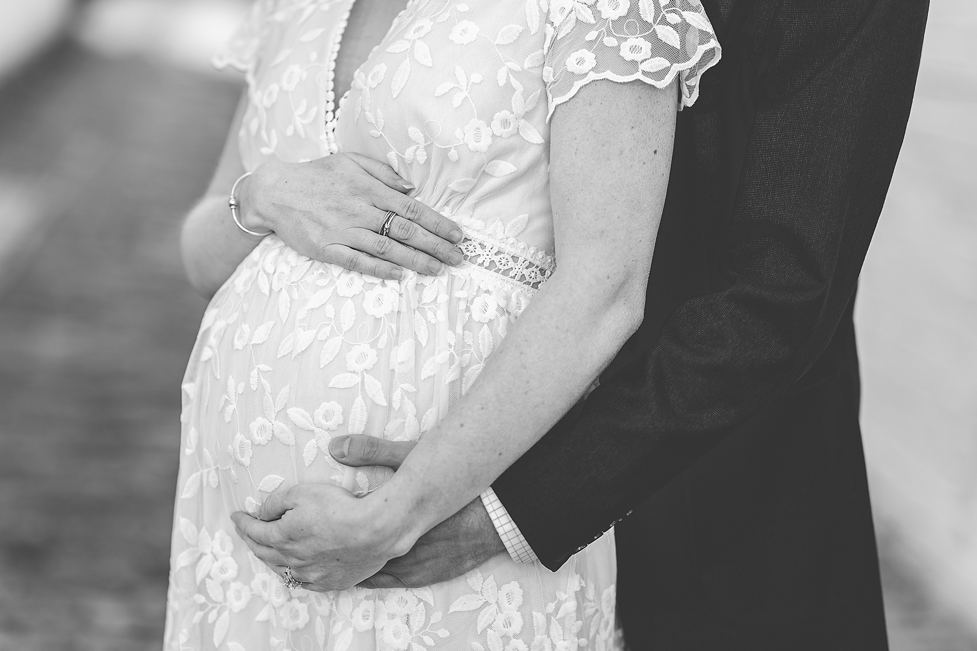 couple holds woman's belly during maternity photos