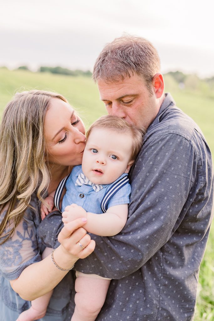 parents hold son and kiss his cheeks during Howard County family photos
