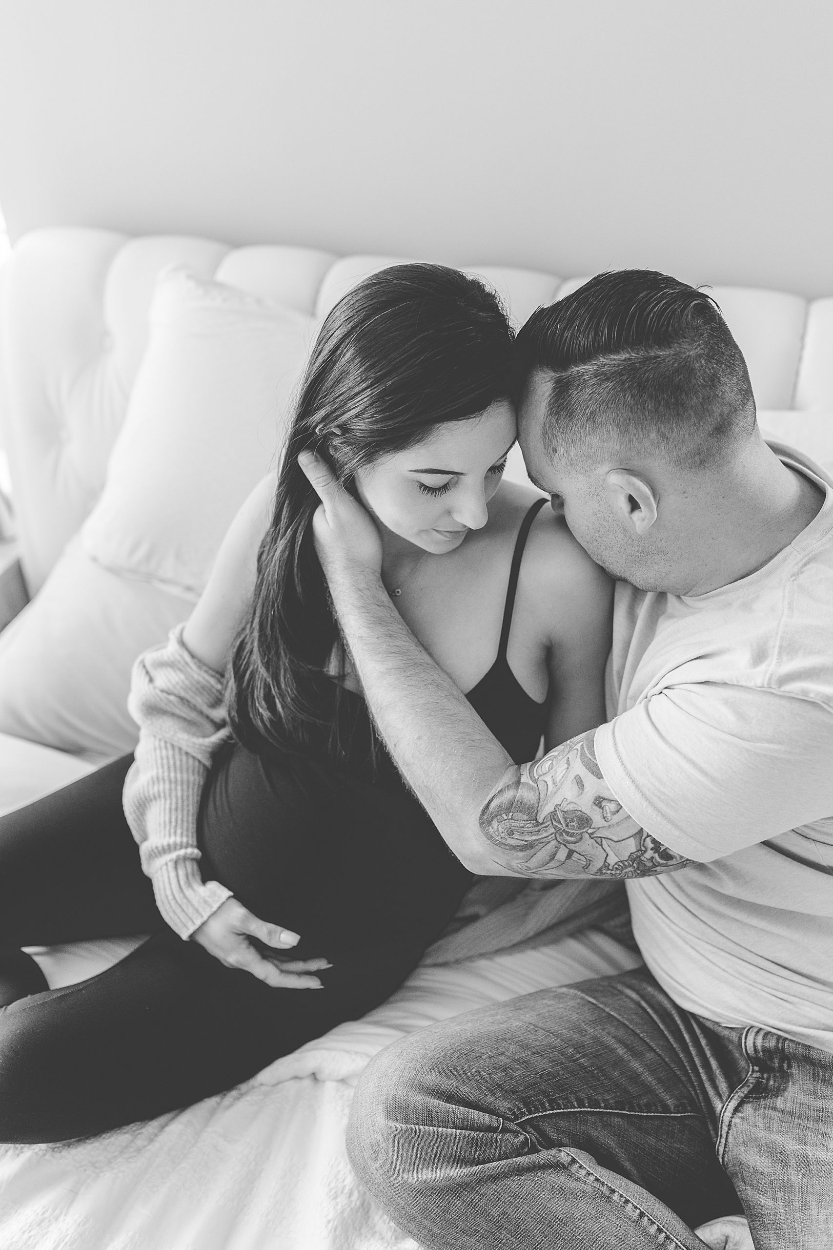 expecting parents sit on couch during at-home maternity session in Annapolis MD