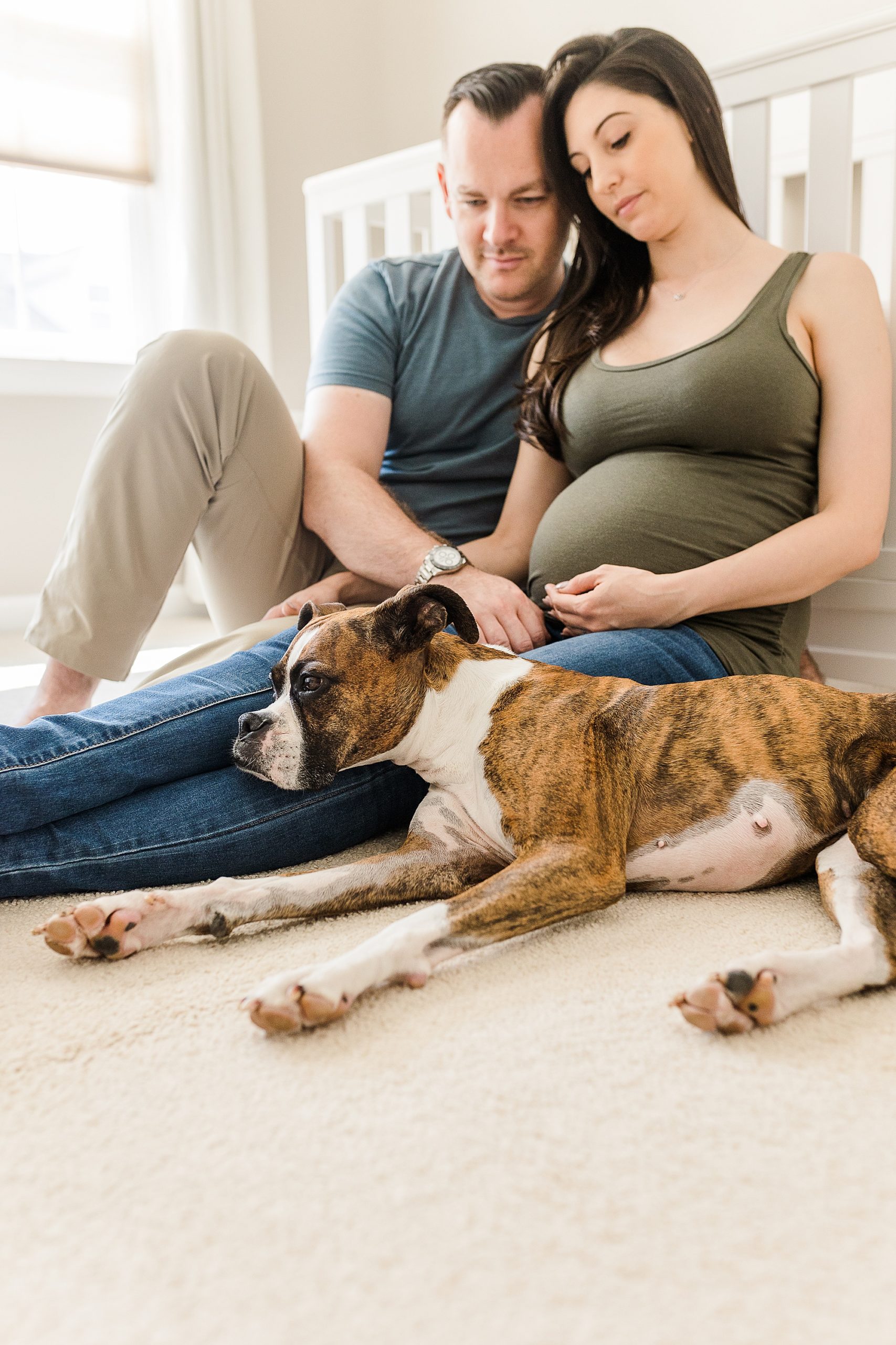 parents sit by crib with dog during at-home maternity session