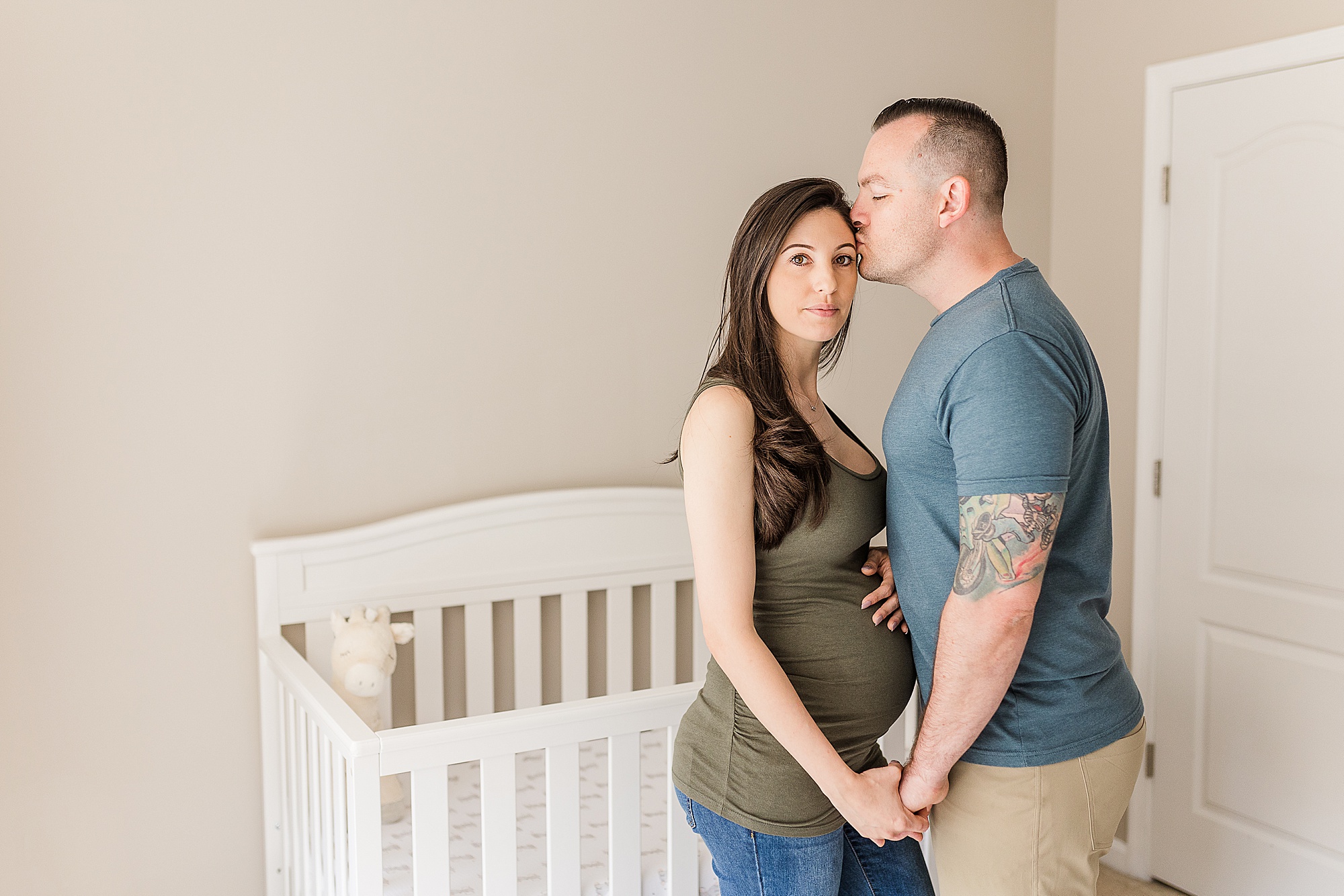 husband kisses wife's forehead during at-home maternity session