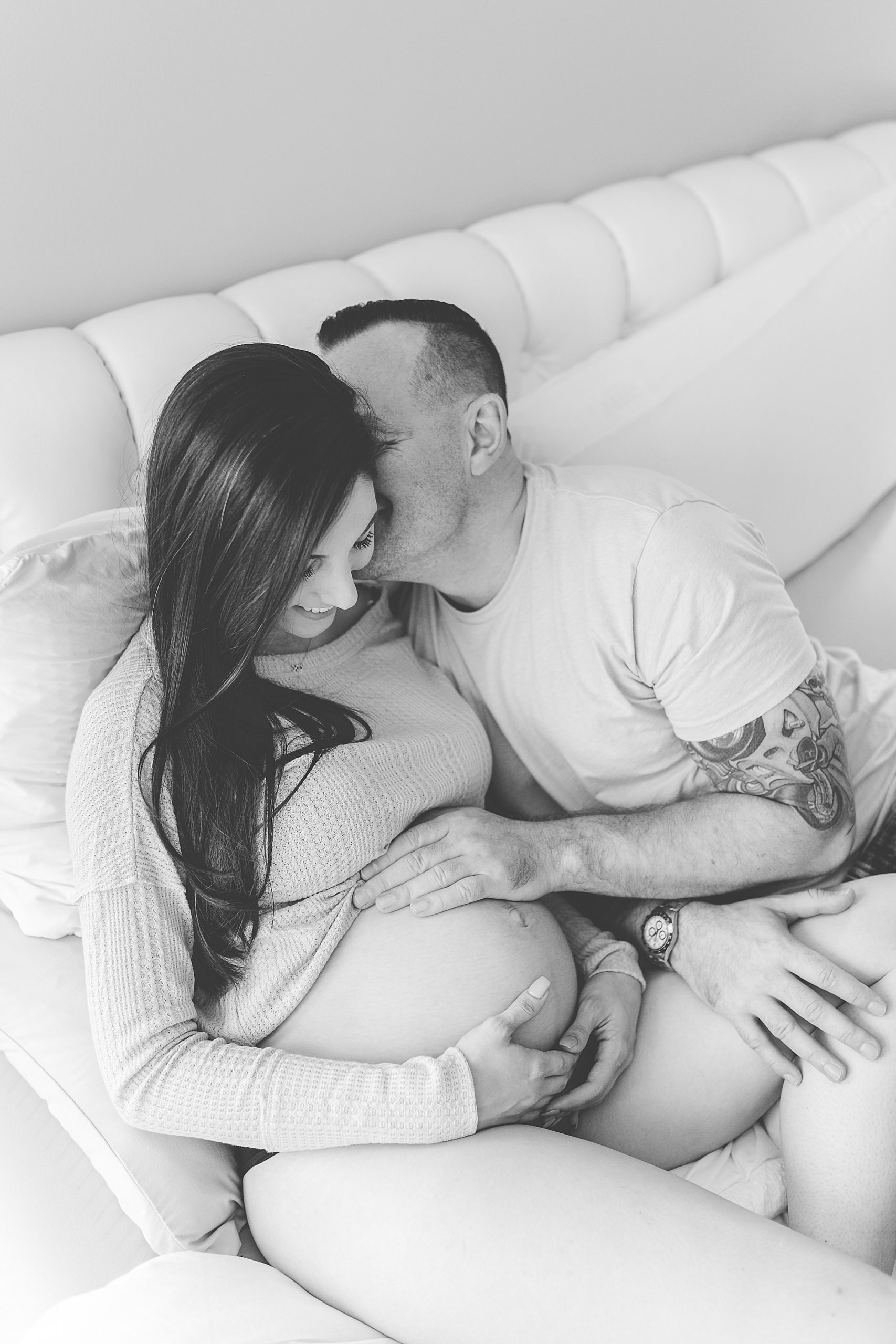 man leans into woman's cheek during at-home maternity session
