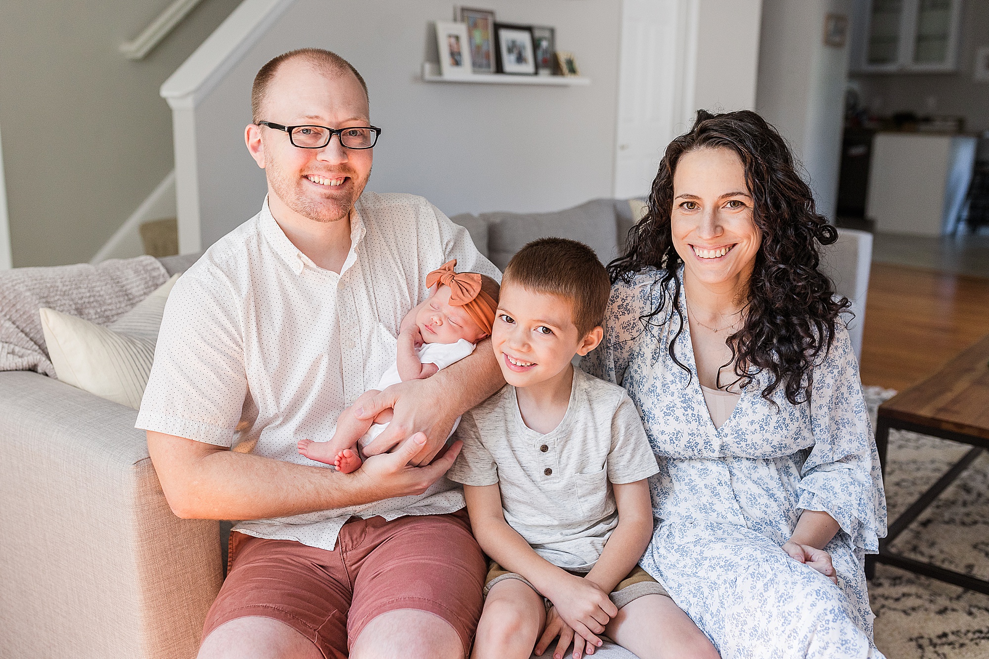 family of four sits on couch during Lifestyle Newborn Session in Annapolis