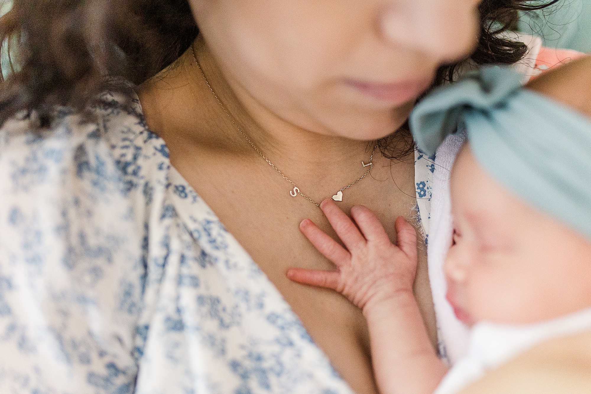 baby holds onto mom's chest during newborn photos at home 