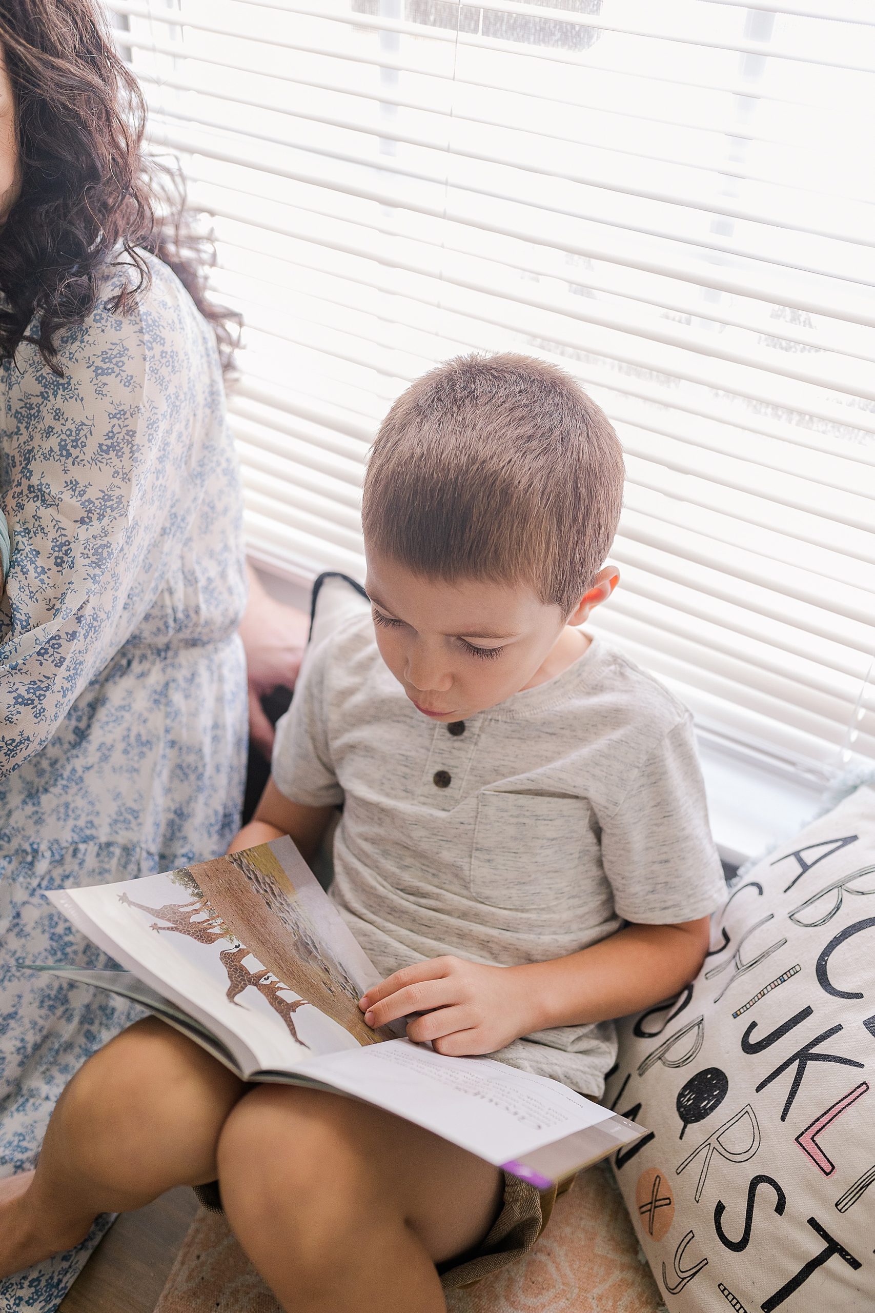 boy reads book to parents during family photos at home 