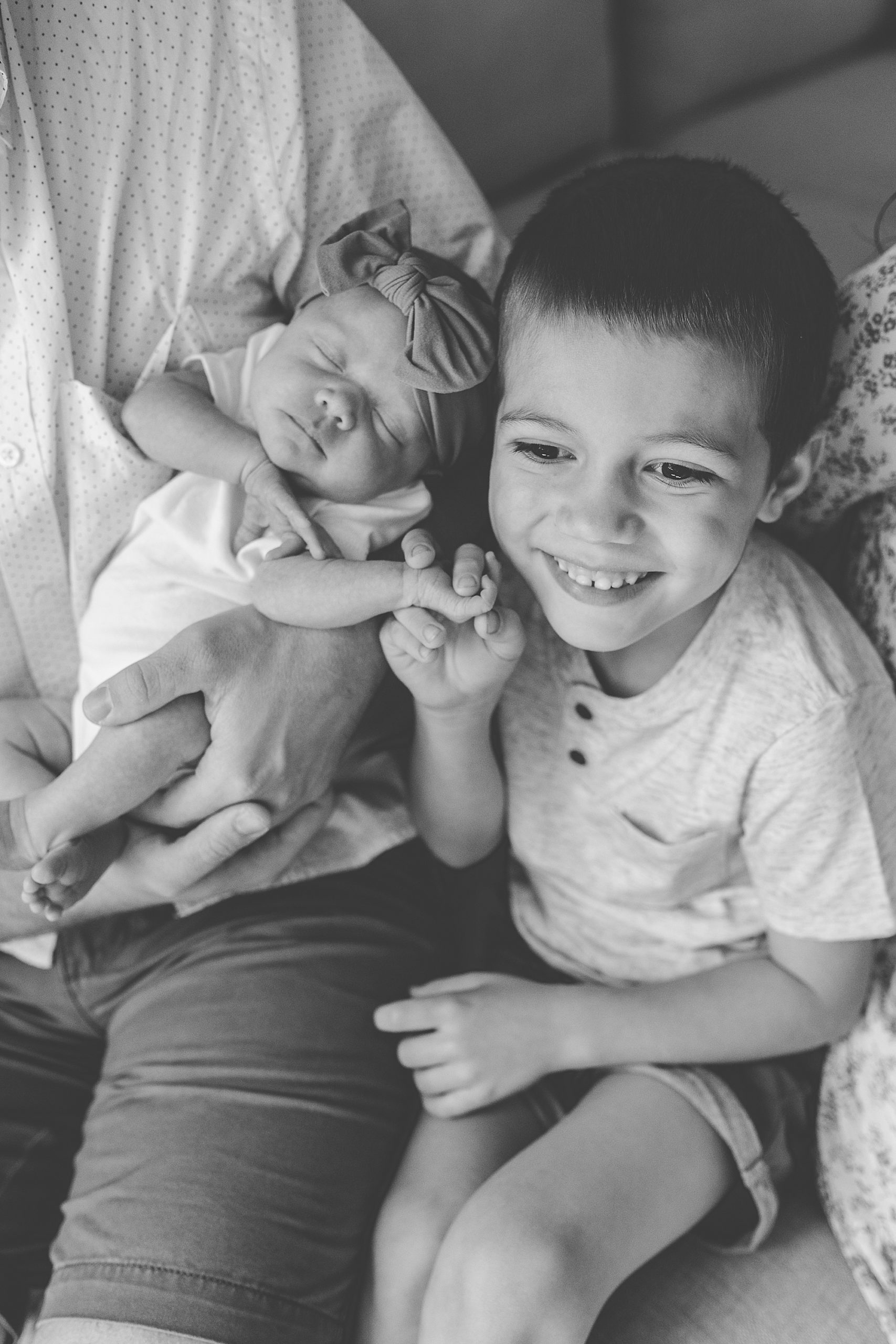 brother holds new sister's hand during Lifestyle Newborn Session in Annapolis
