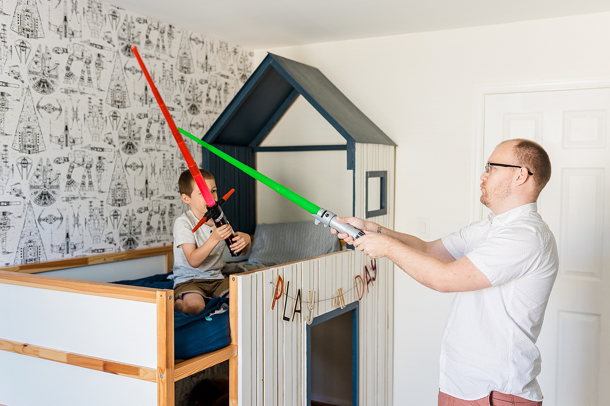 dad and son play with lightsabers during at home family photos 