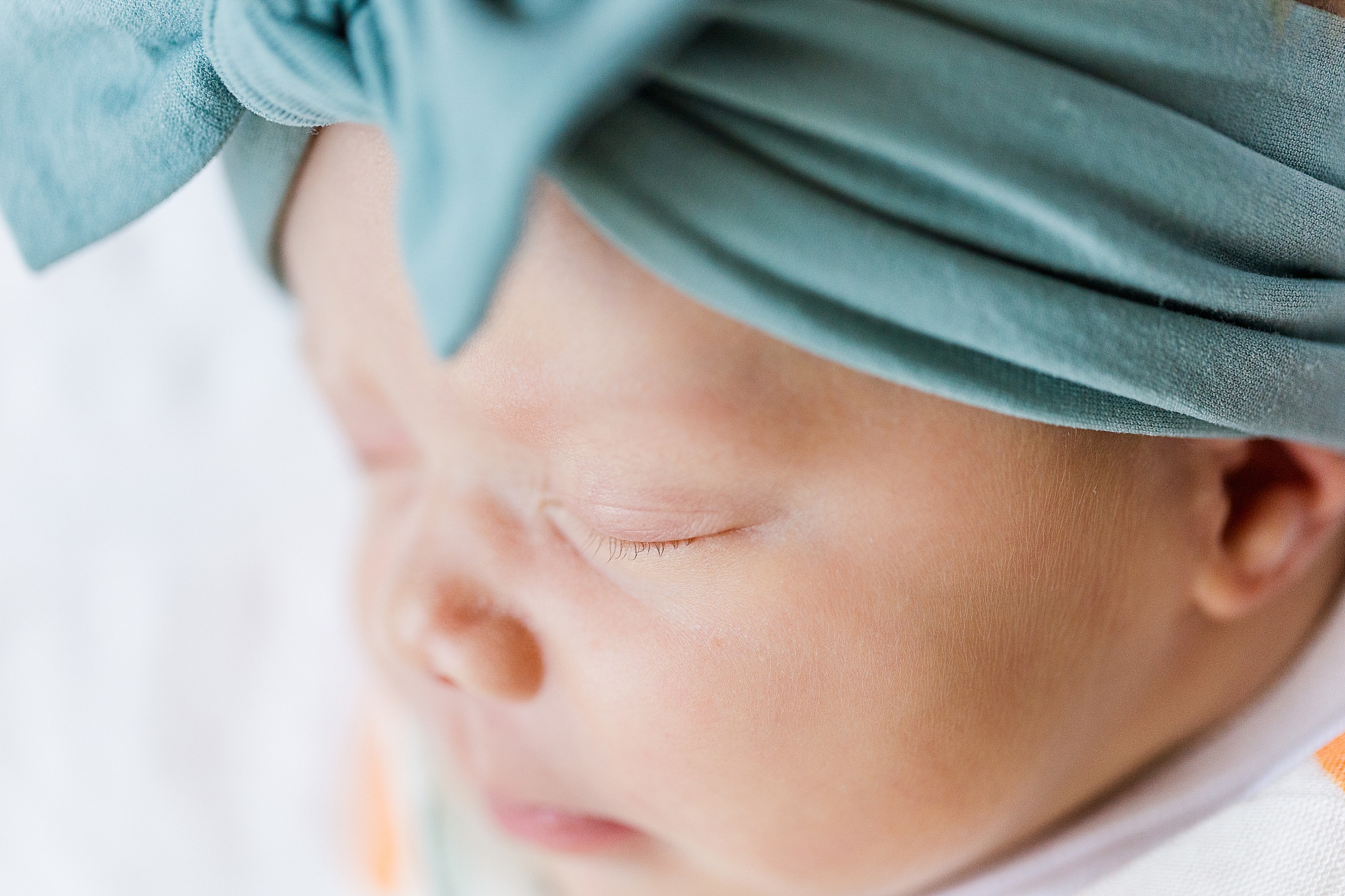 baby sleeps with teal bow during MD newborn session 