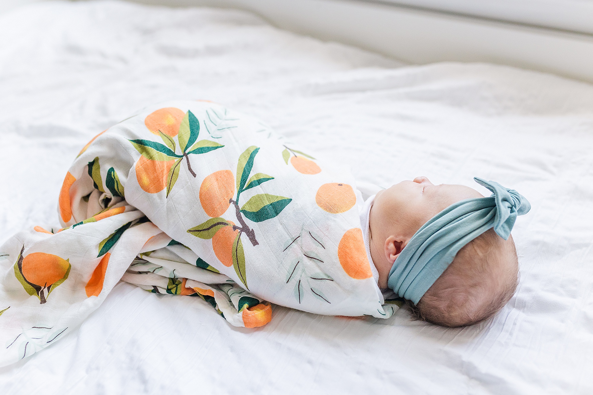 baby girl in citrus wrap sleeps on bed during Lifestyle Newborn Session in Annapolis