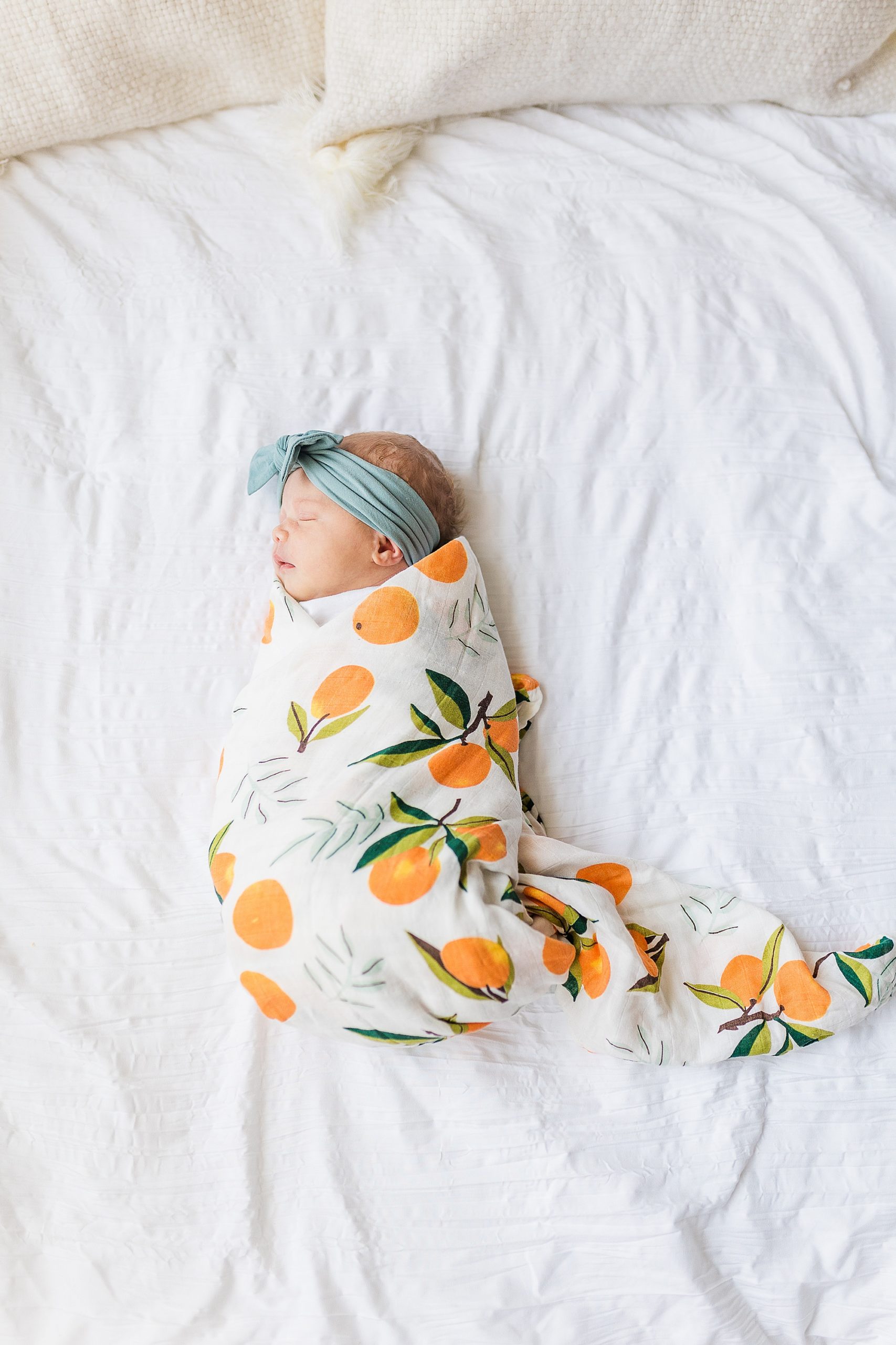 baby girl in citrus wrap lays on bed during newborn photos at home 