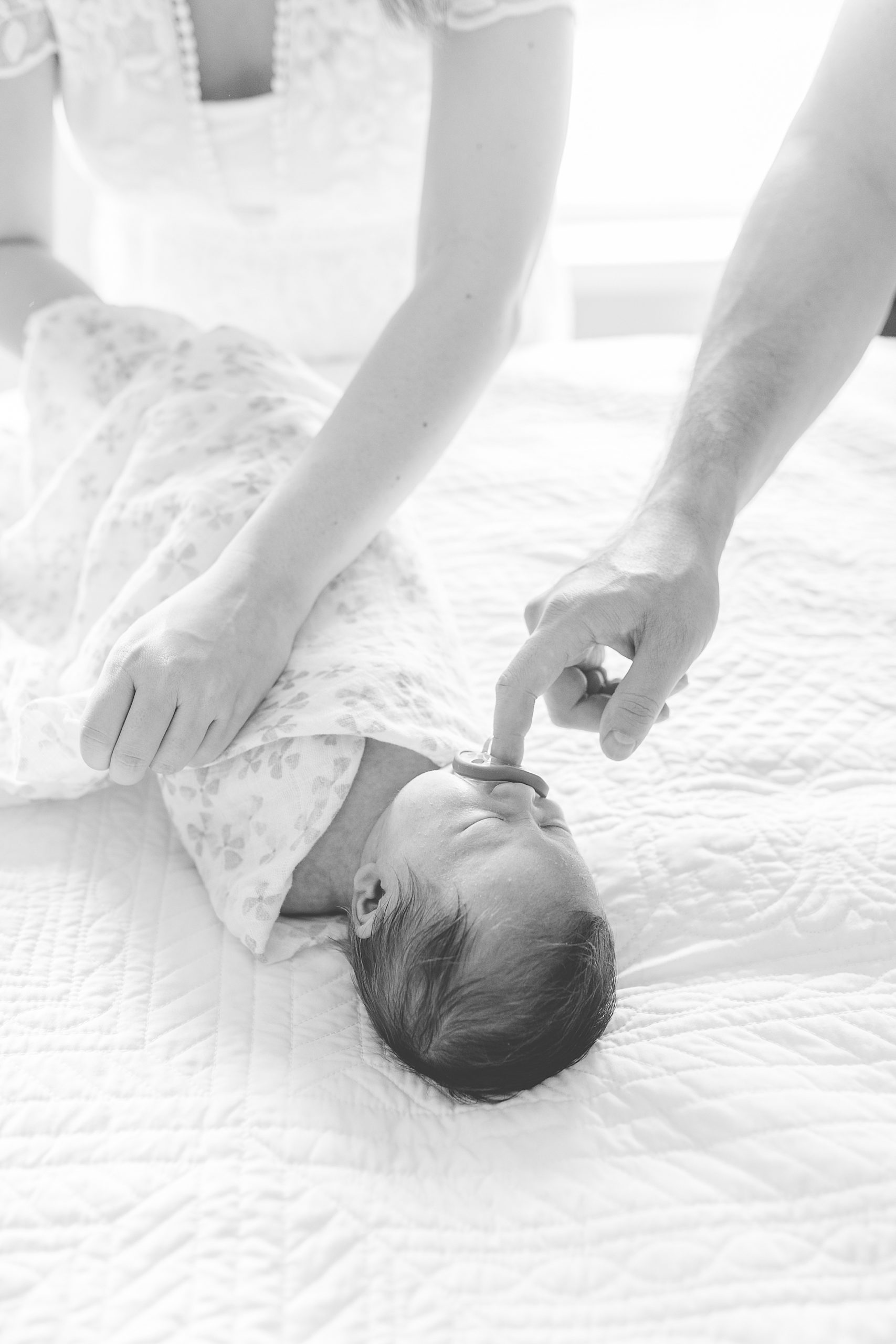 parents wrap baby girl during lifestyle newborn portraits
