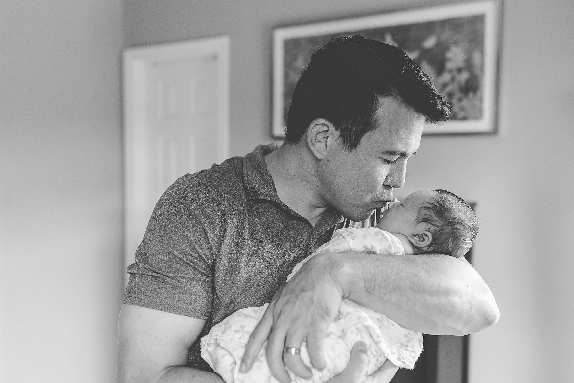 dad kisses new daughter at home during lifestyle newborn portraits