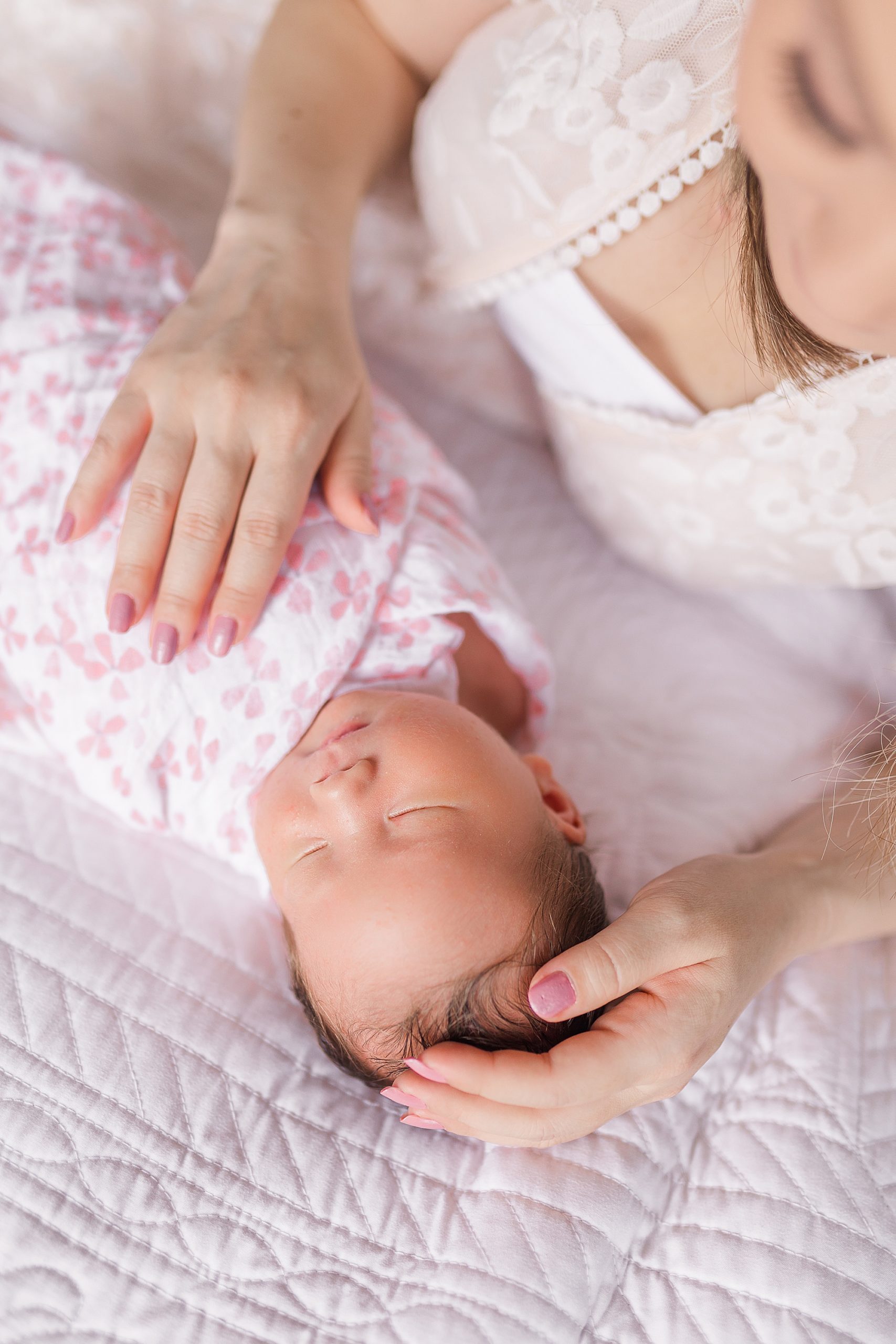 mom rubs daughter's belly in pink wrap during newborn session at home