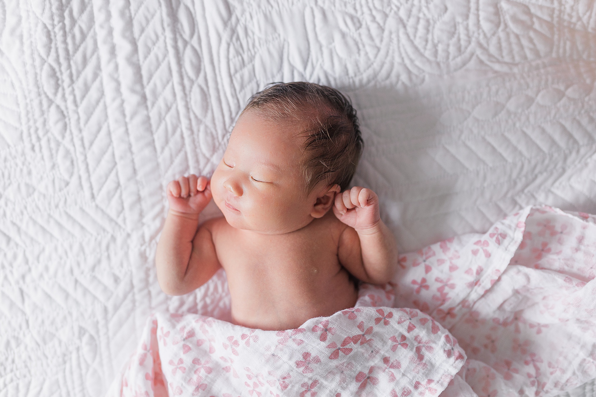 baby girl lays in pink floral wrap during lifestyle newborn portraits