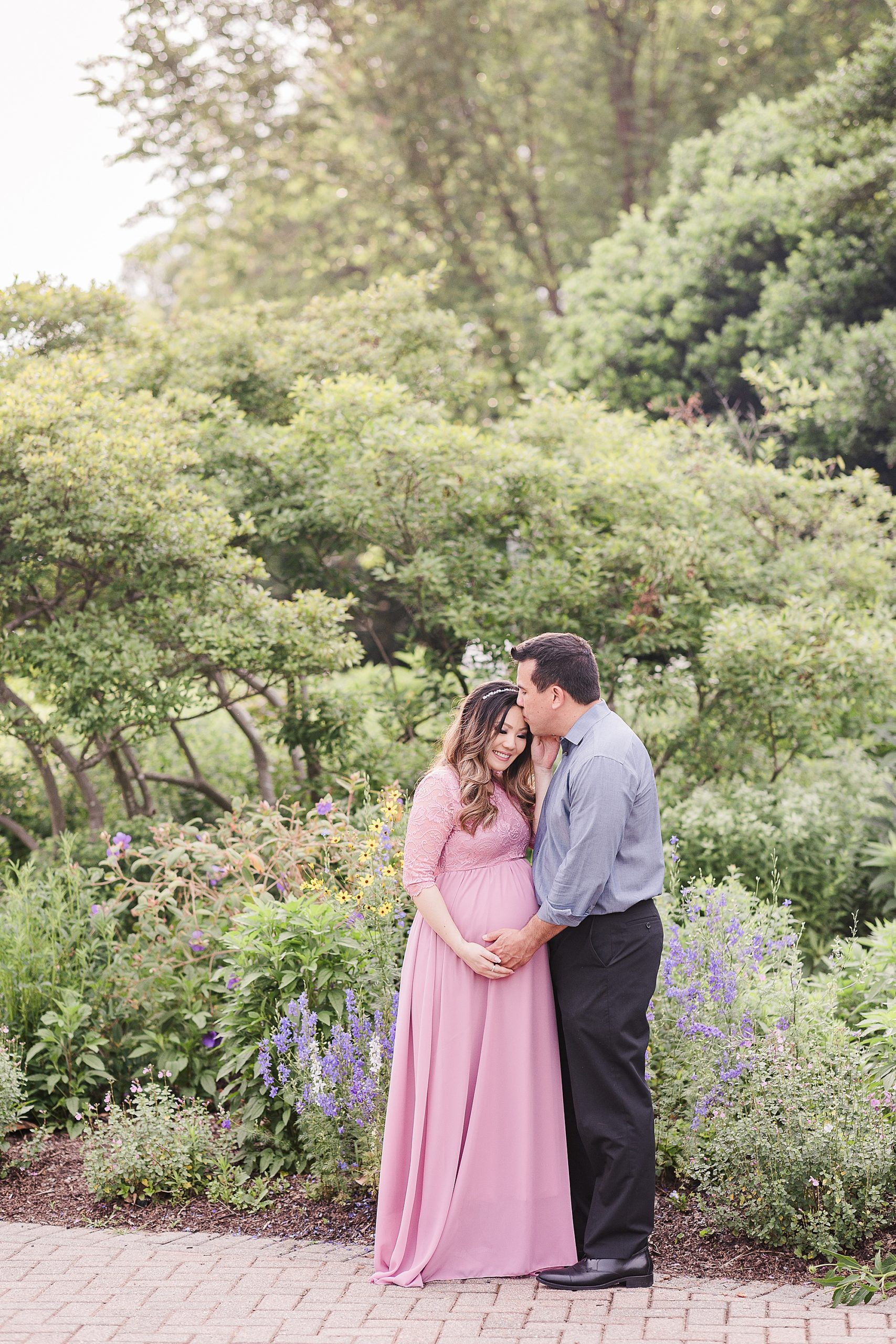 husband kisses wife's forehead during Green Spring Gardens maternity portraits 