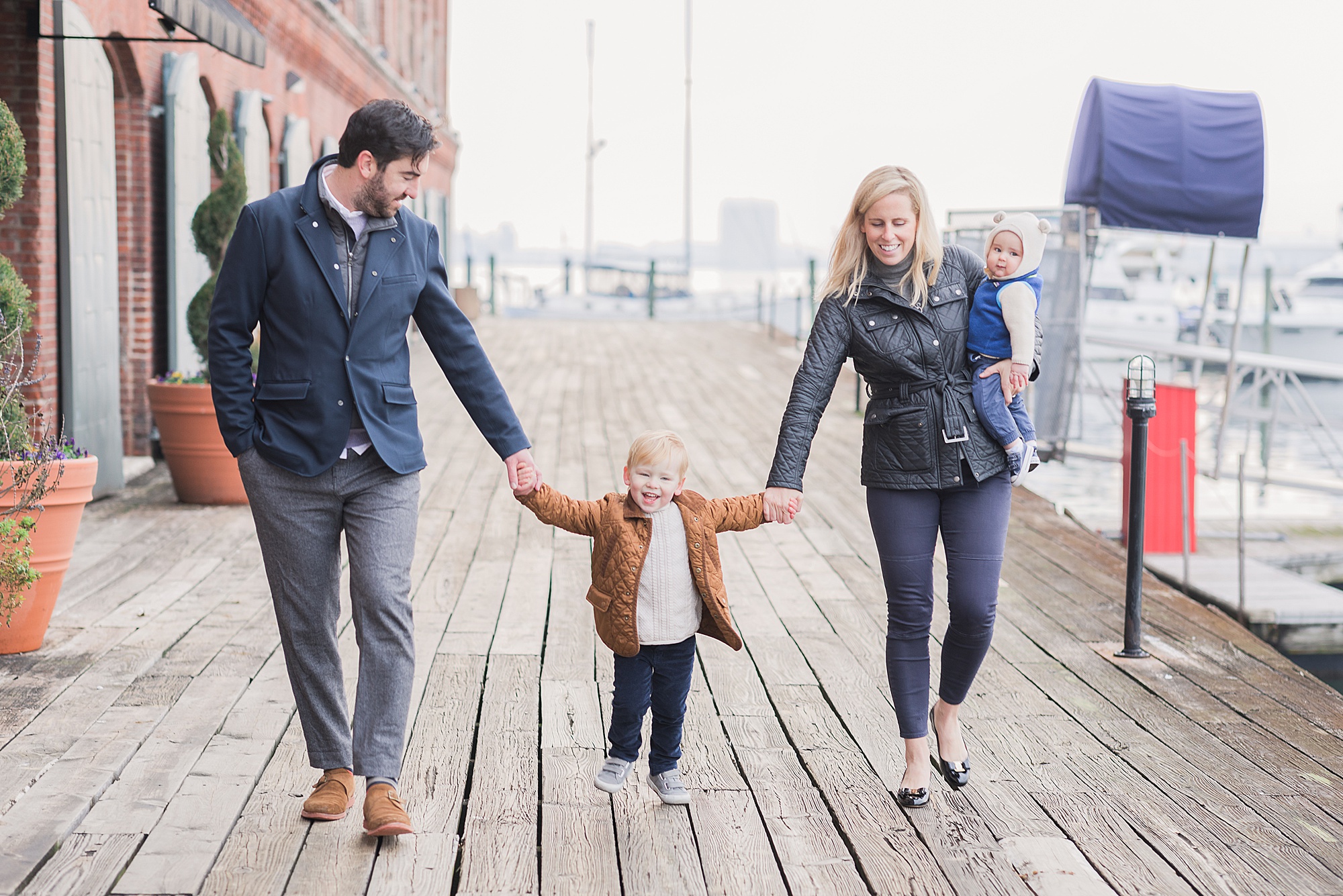 family walks along wharf in Fells Point during family photos 
