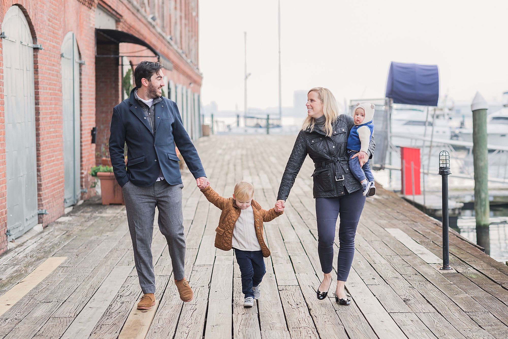 family holds hands walking on dock in Fells Point MD