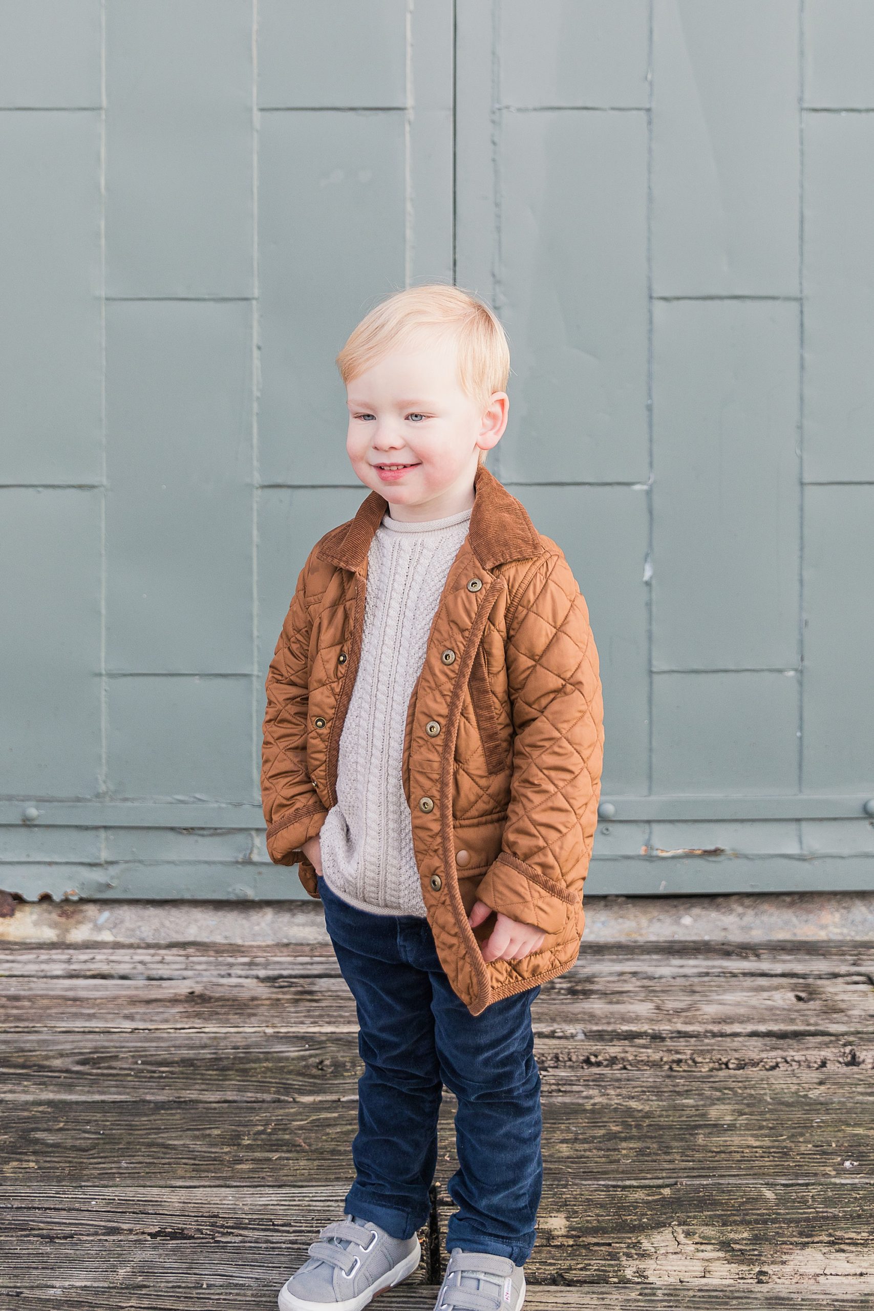 toddler poses in copper jacket during MD family portraits 