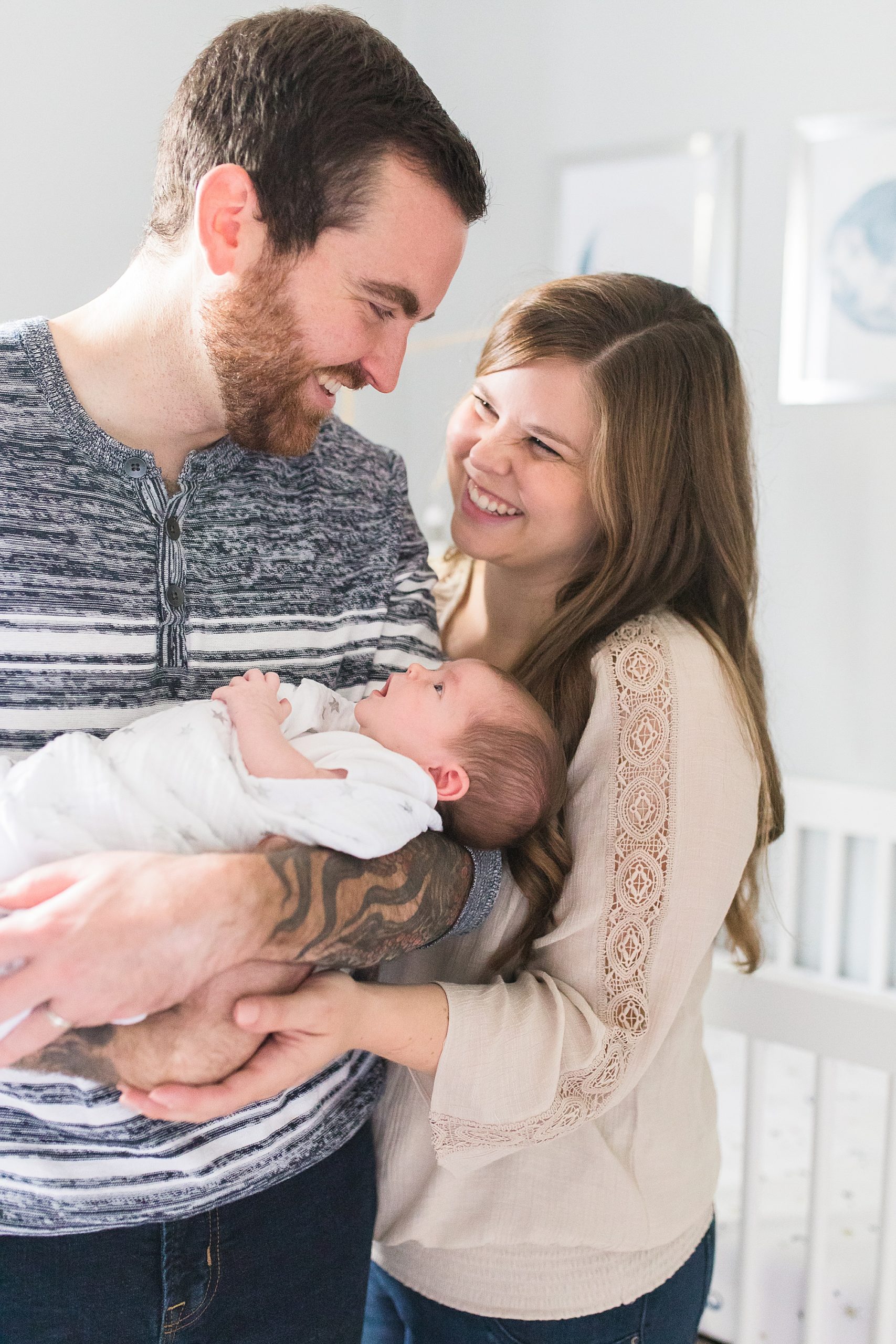 parents smile while holding baby between them during Annapolis lifestyle newborn session