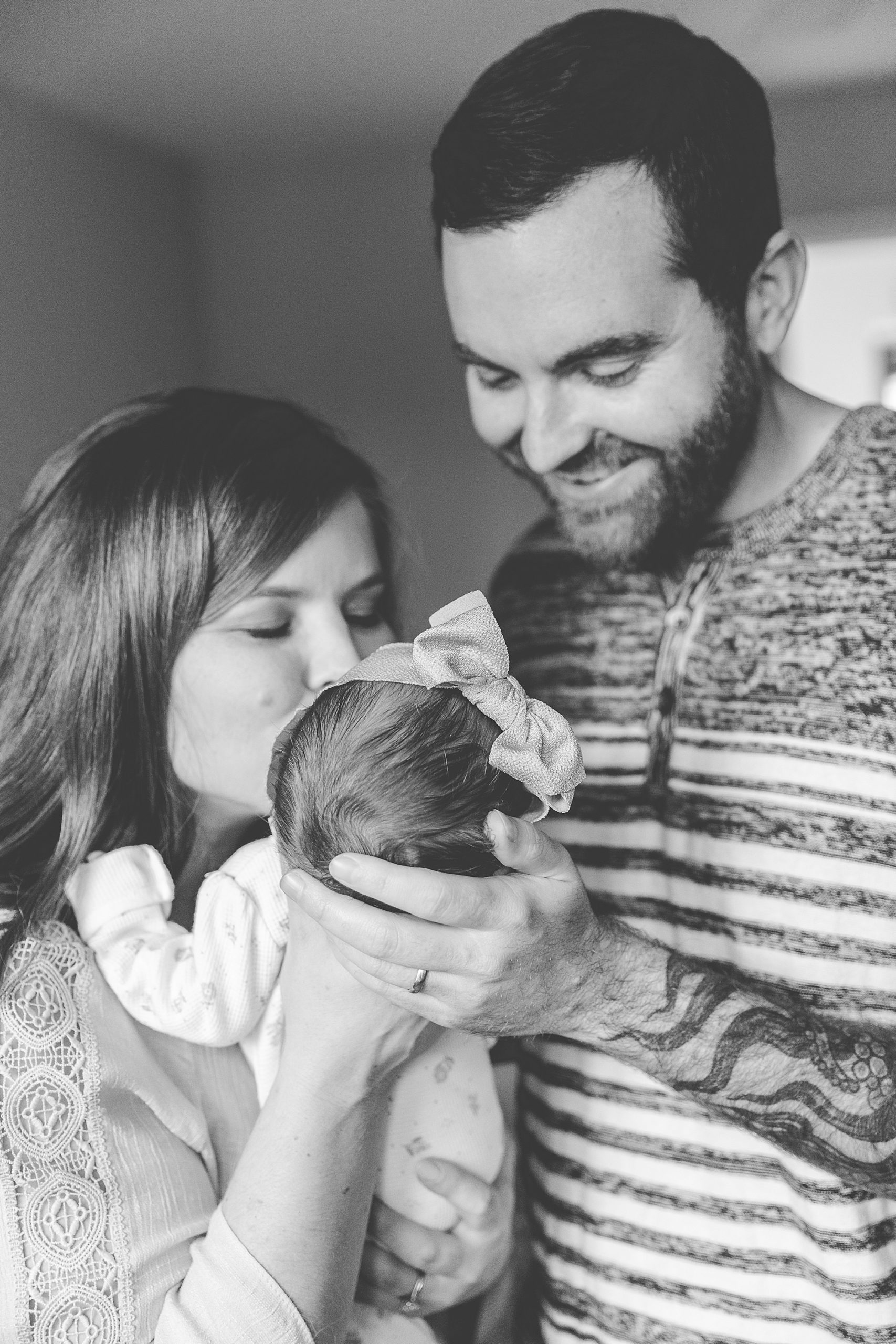 new parents kiss baby girl during lifestyle newborn photos 