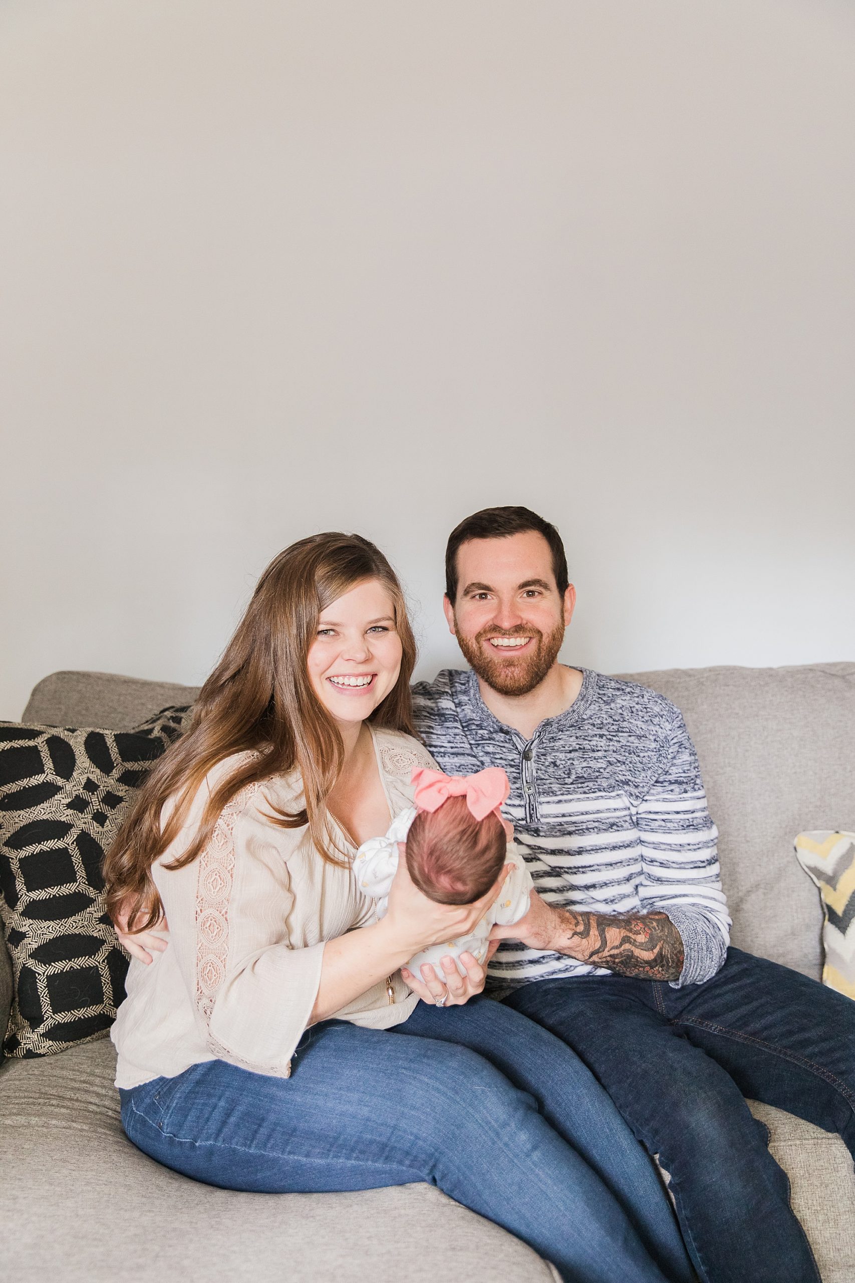 family sits on couch with new baby girl during Annapolis lifestyle newborn session