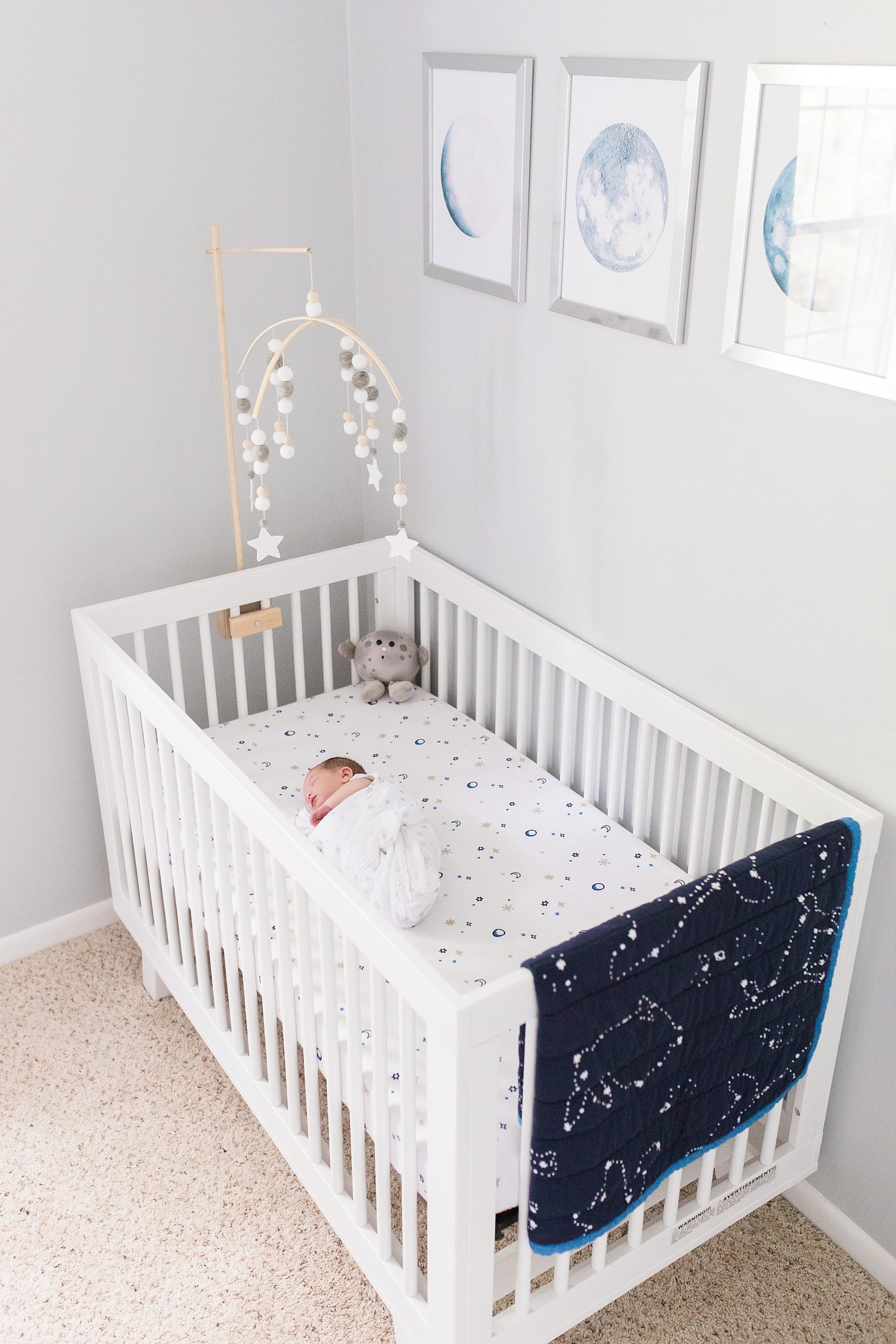 baby sleeps in white crib with navy blanket