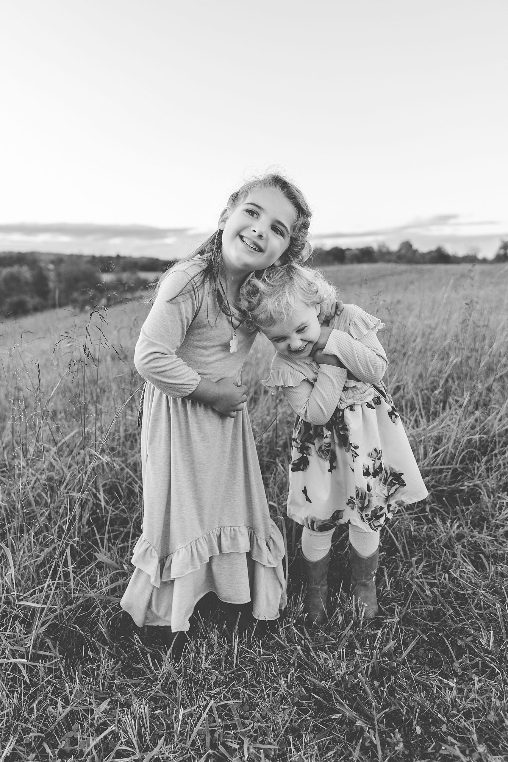 sisters hug in field during Howard County Conservancy fall family session