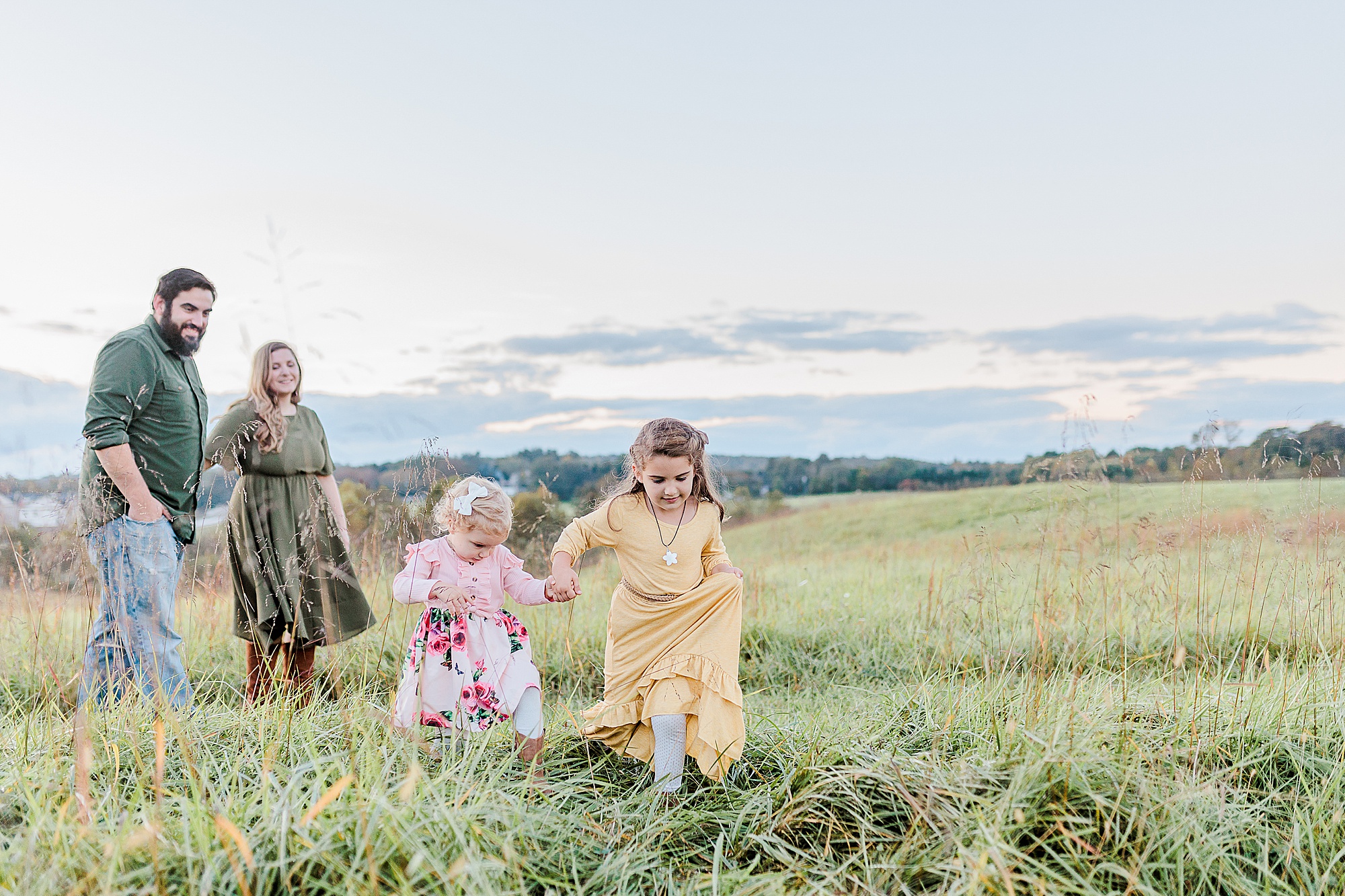 little girls run through grass during fall family photos