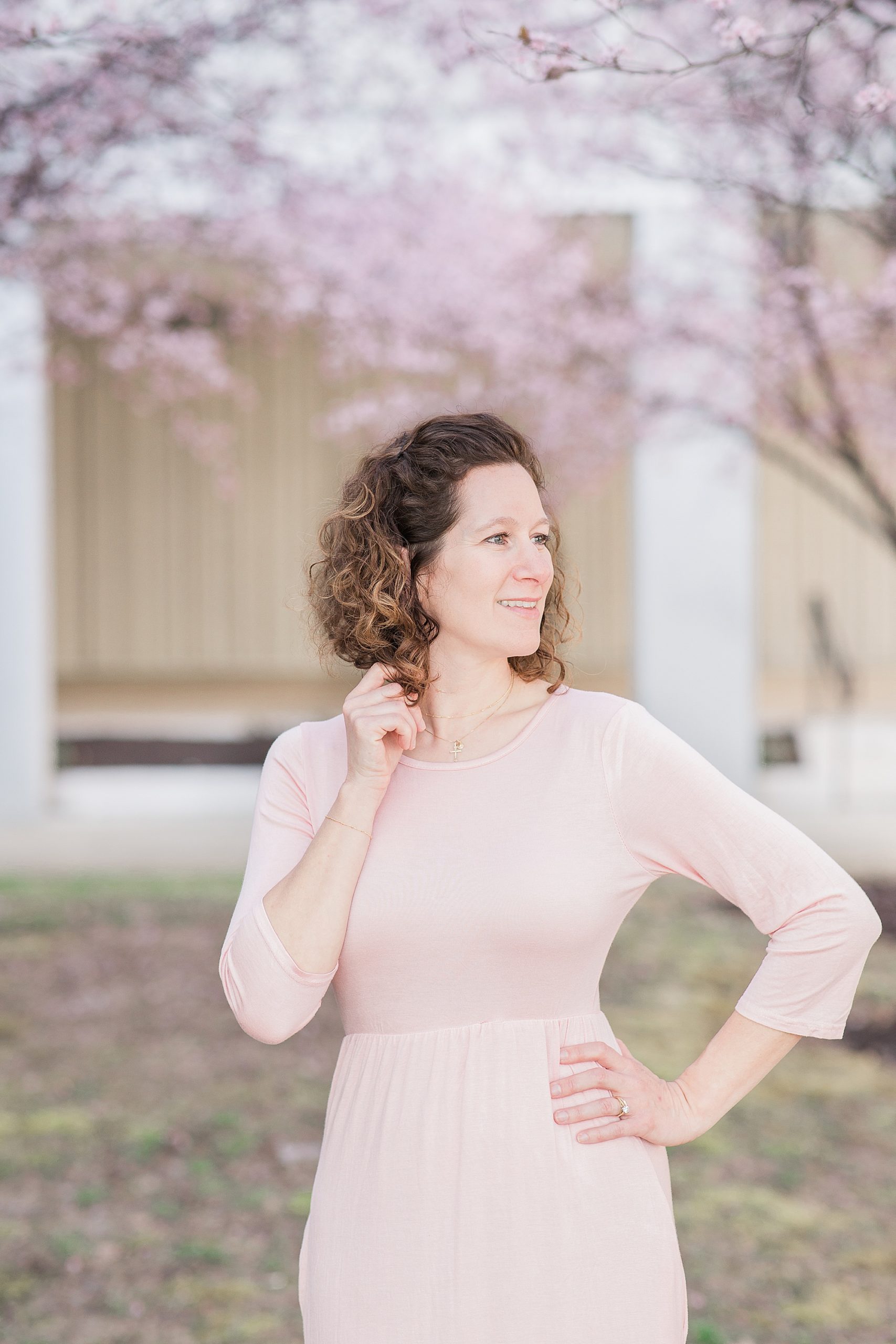 woman in pink gown poses under cherry blossom tree 
