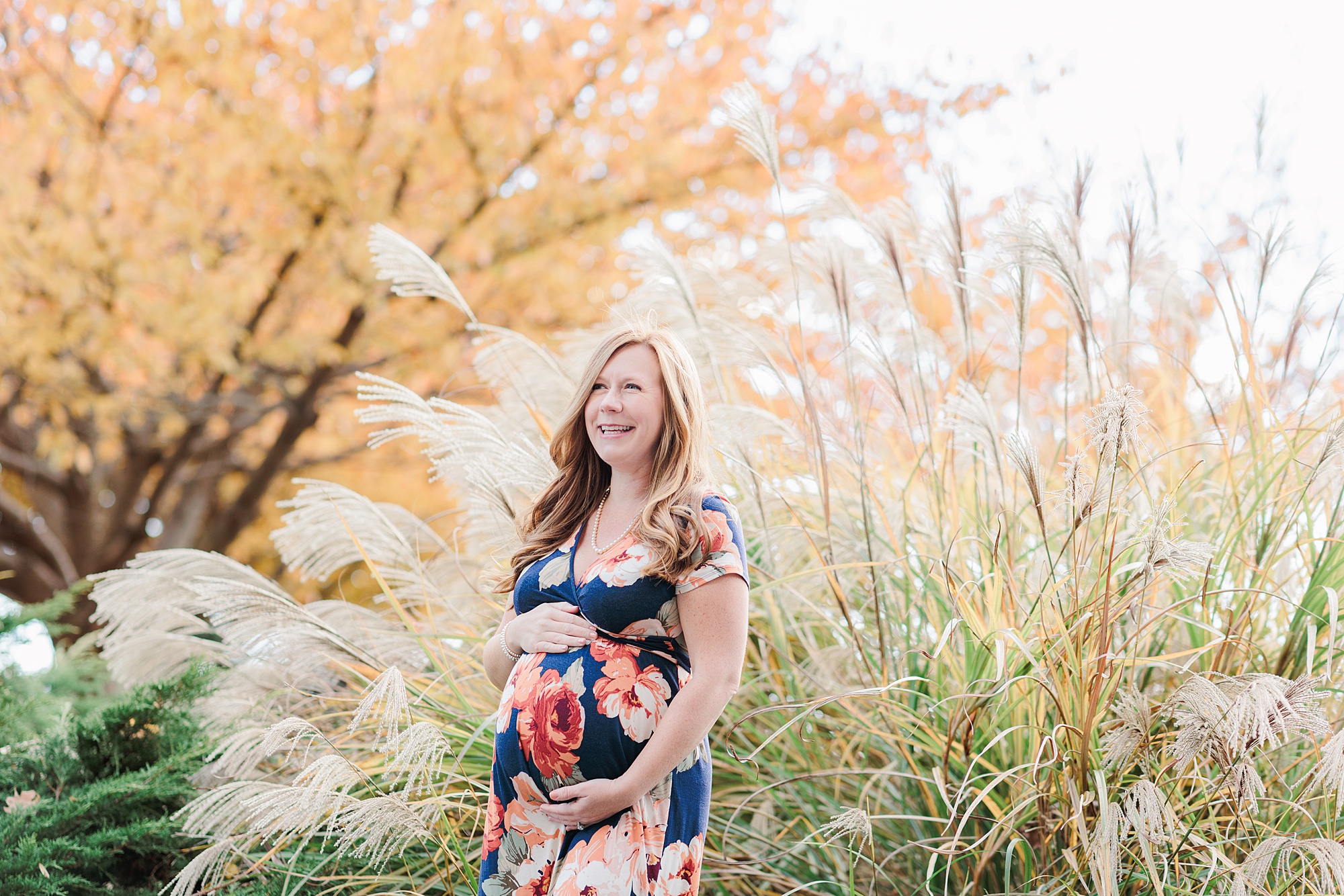 pregnant woman laughs during fall maternity portraits in Ellicott City