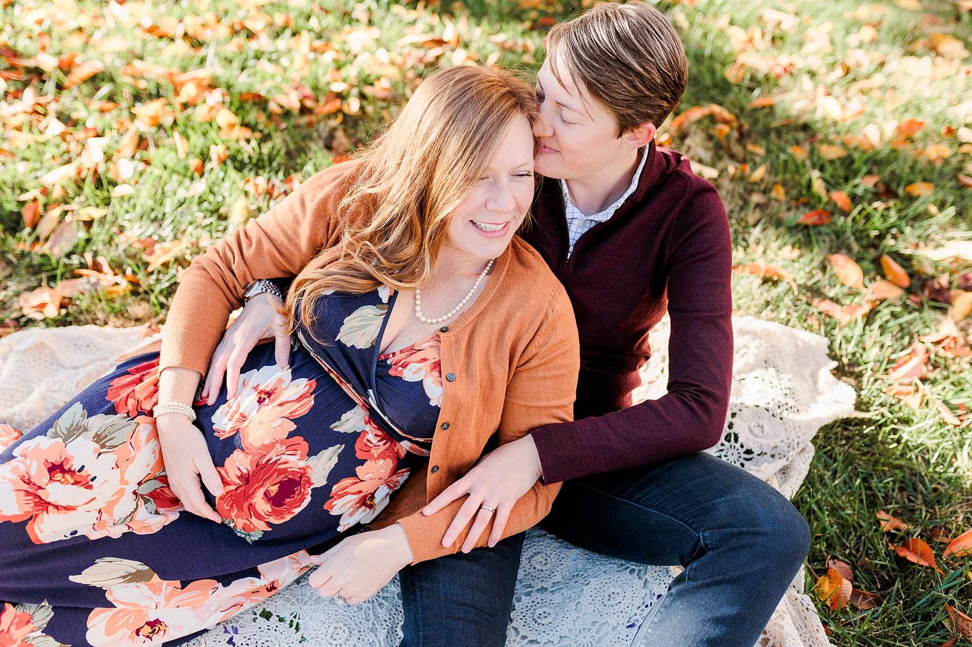 women lay on blanket during fall maternity portraits in Ellicott City