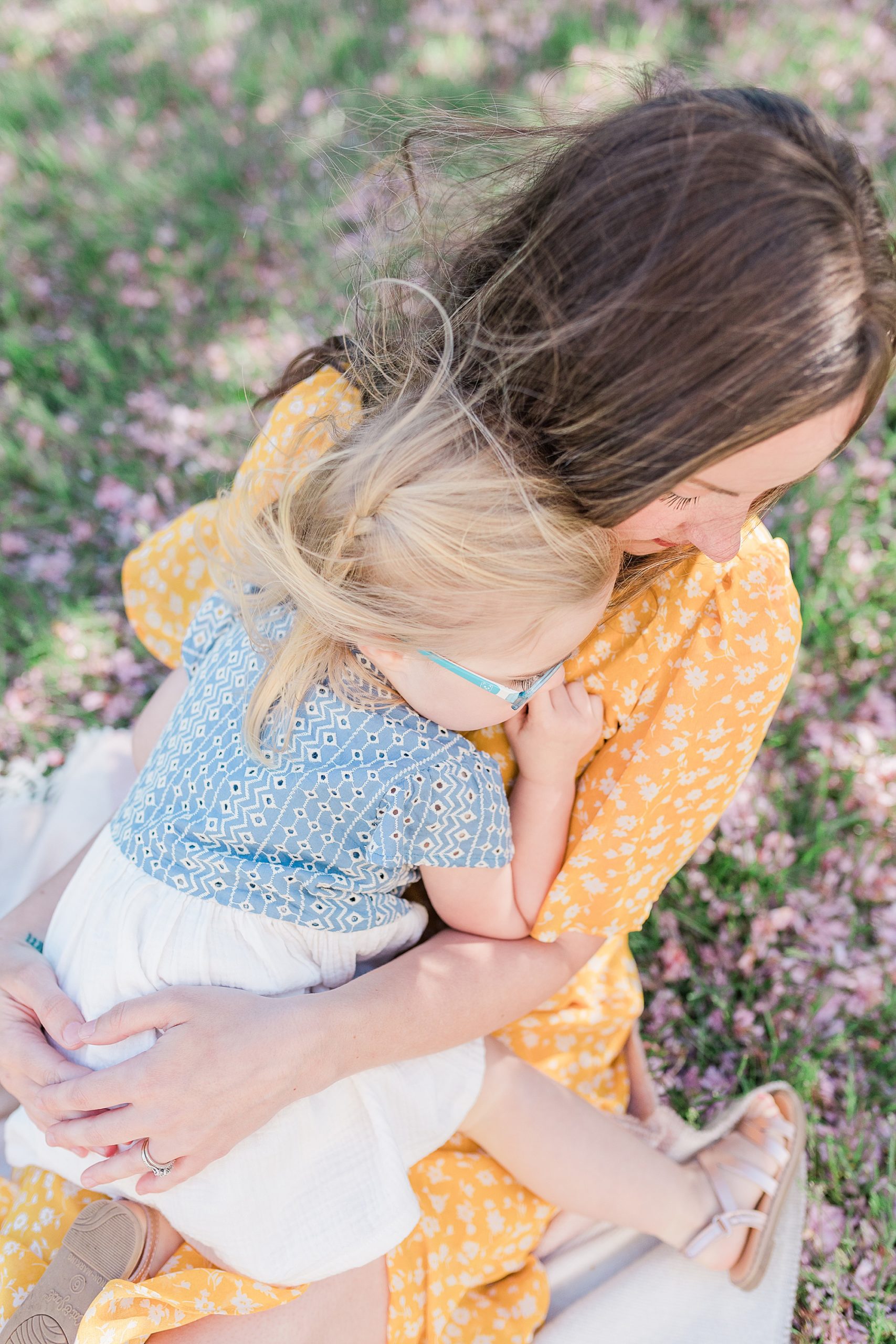 mom and daughter hug during spring photos under trees