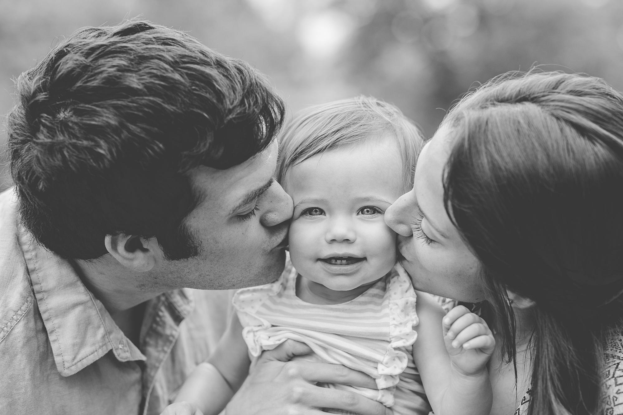 parents kiss toddler on cheek during milestone photos