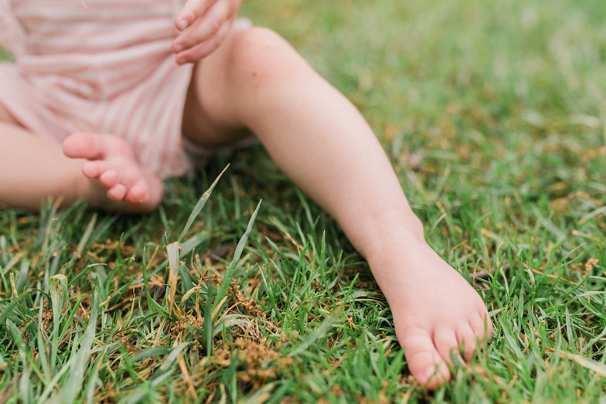 toddler sits in grass at Sherwood Gardens