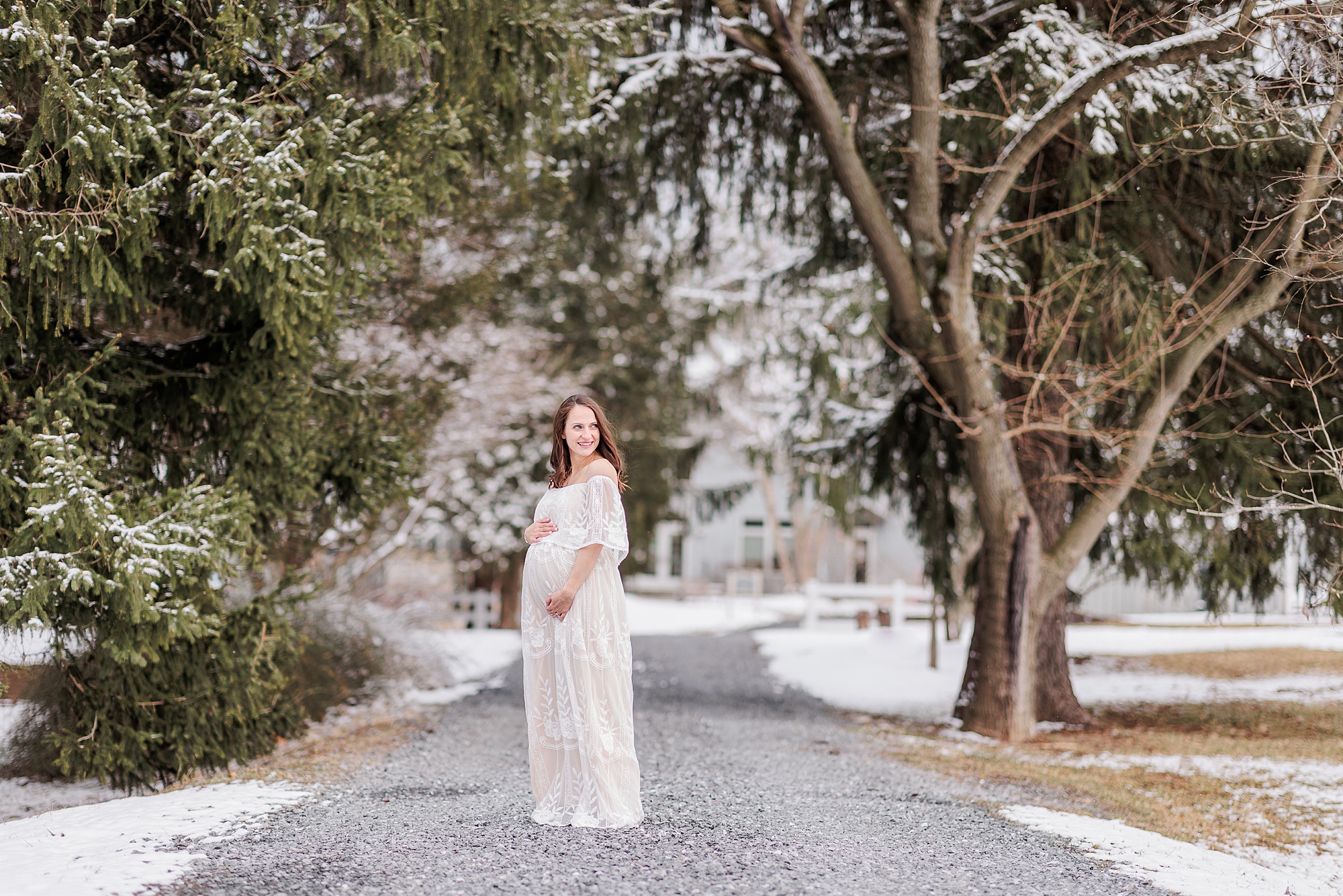 woman stands on driveway holding belly during Howard County Snowy Maternity Session