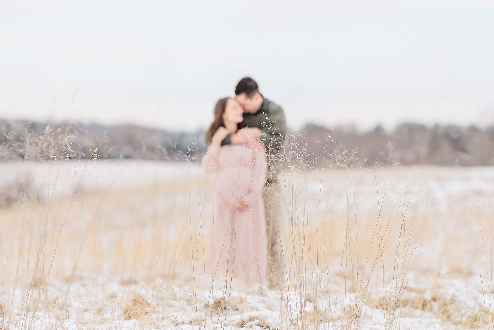 husband and wife hug in the snow during Howard County MD maternity photos
