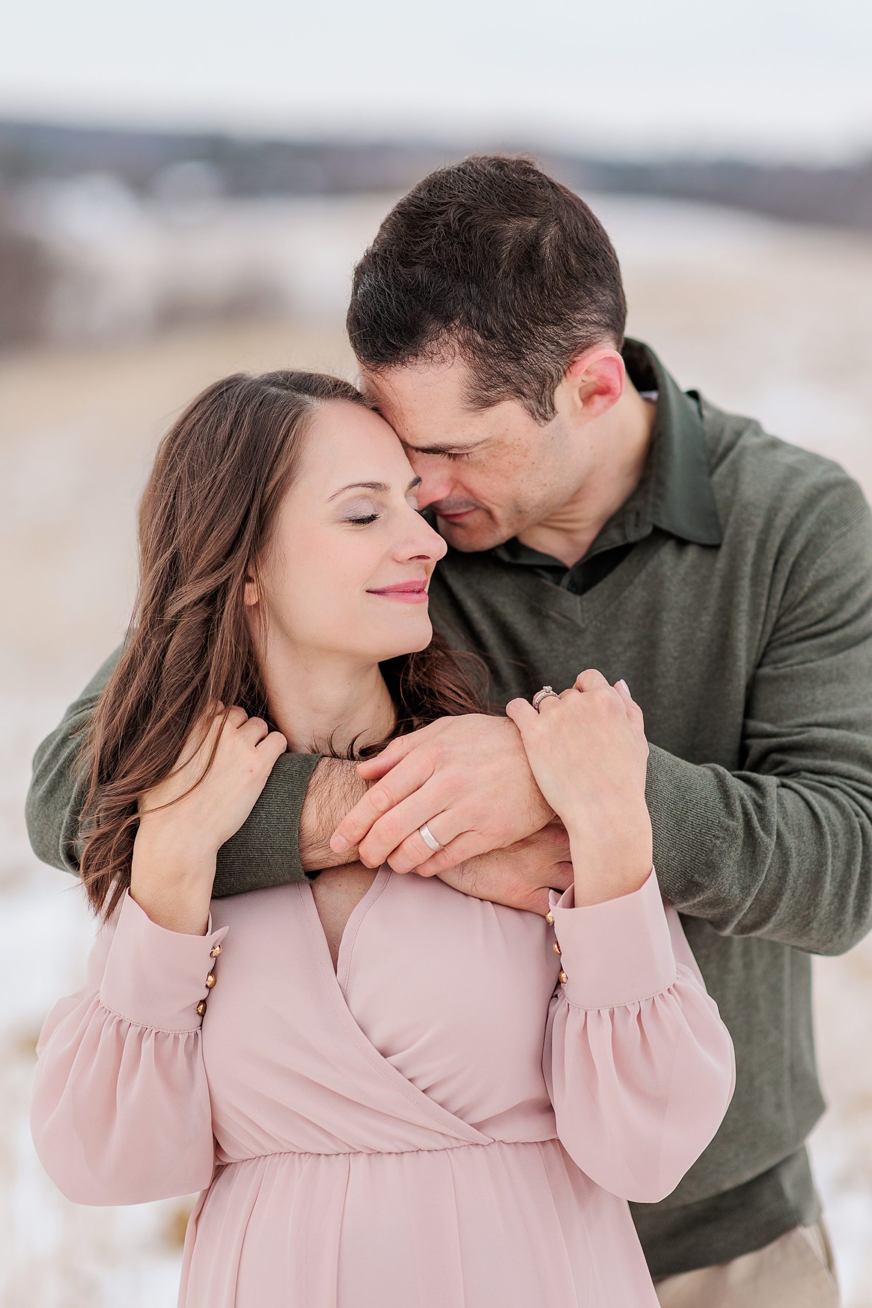 couple hugs in snow during maternity photos