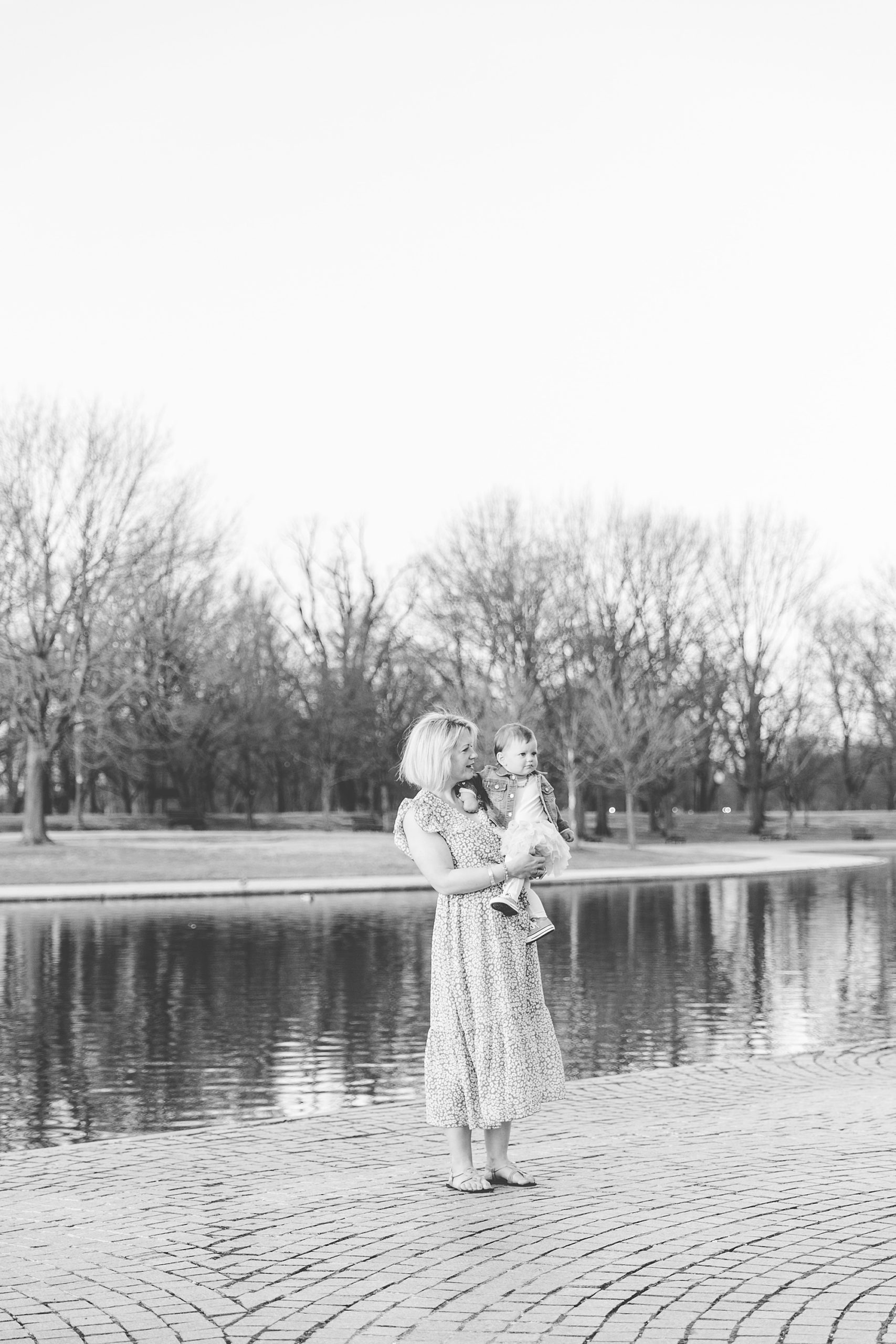 mom stands with baby girl on hip during Constitutional Gardens family portraits