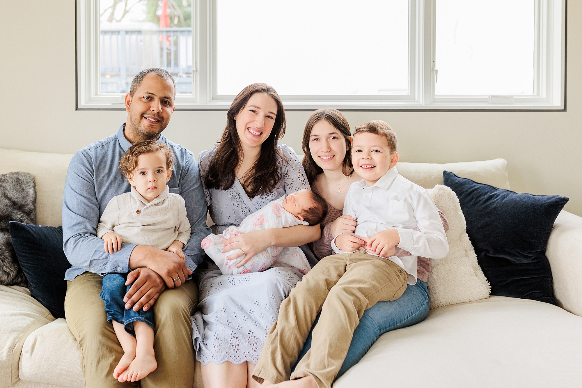 family of six sits on couch during lifestyle photos at home