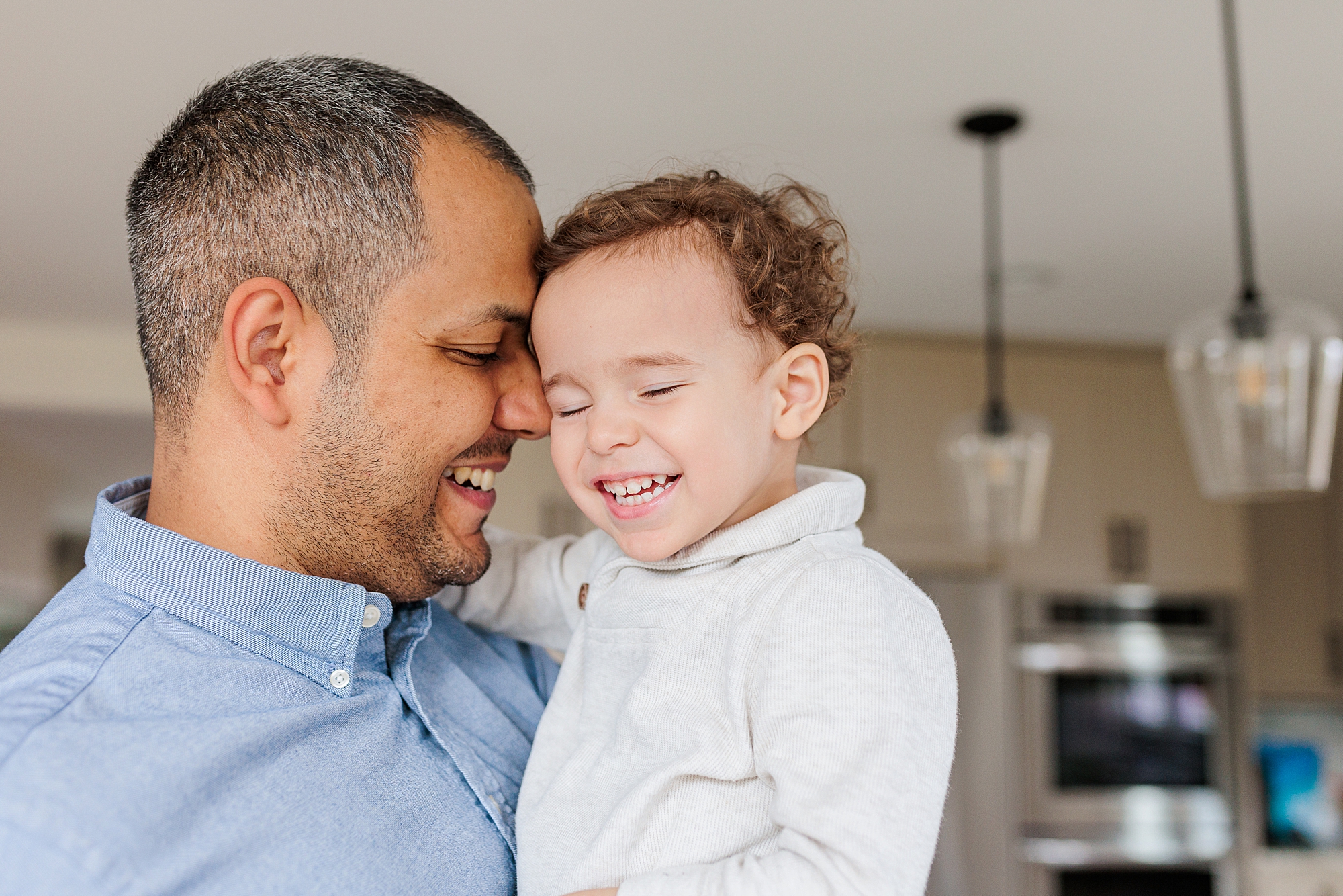 dad and toddler laugh in kitchen during lifestyle photos