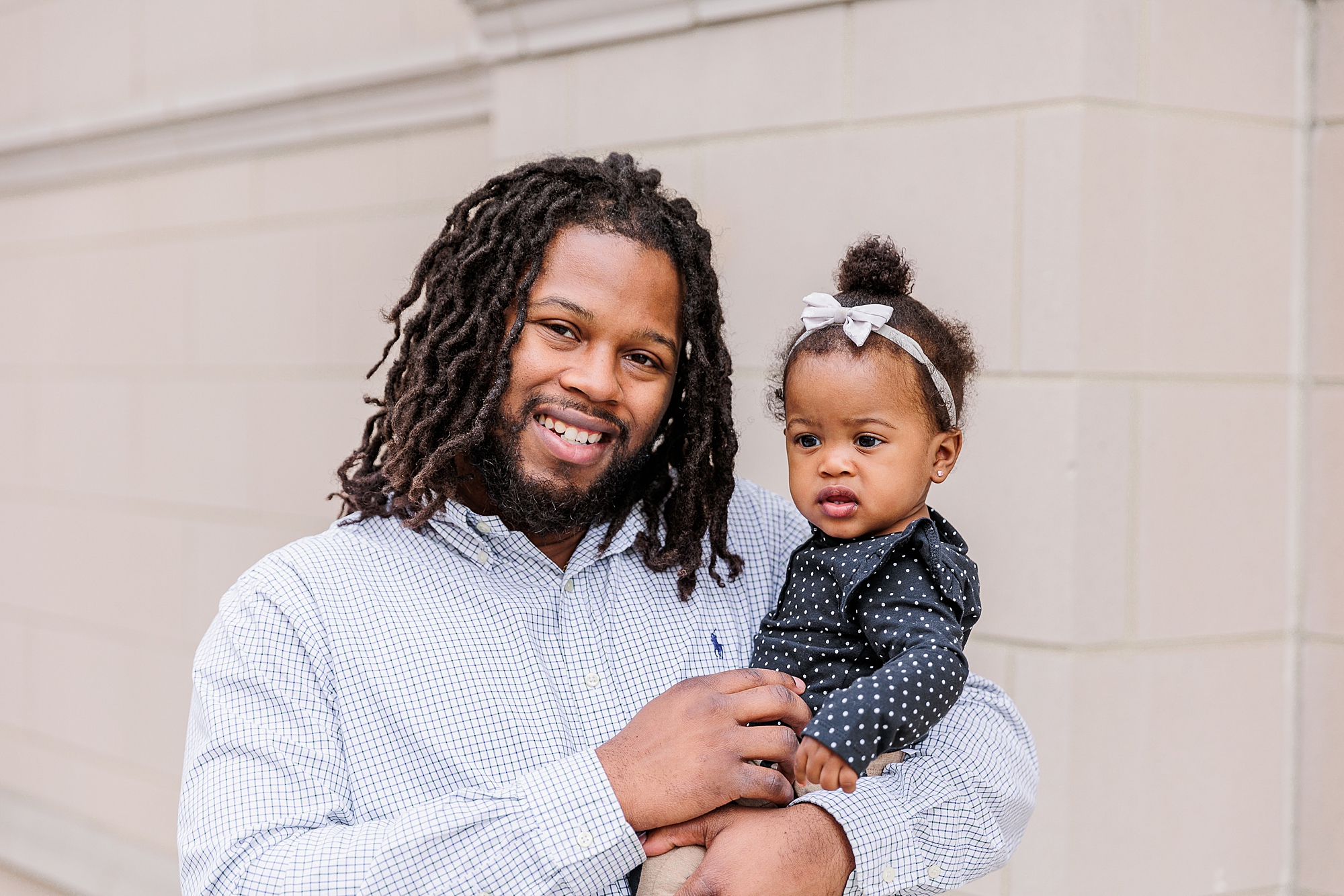 dad poses with daughter along white wall during Annapolis family portraits