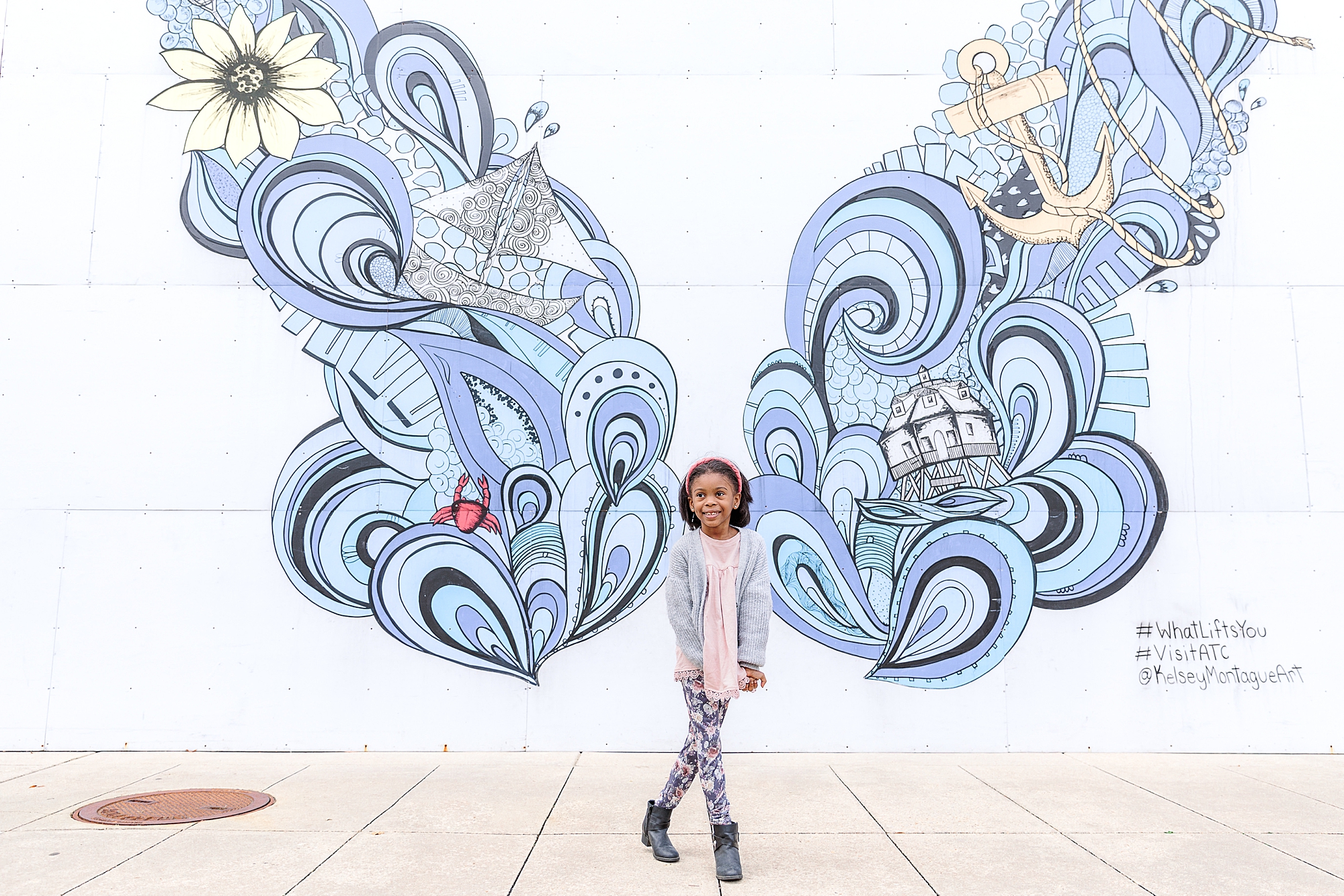 girl stands in front of blue butterfly wall decor 